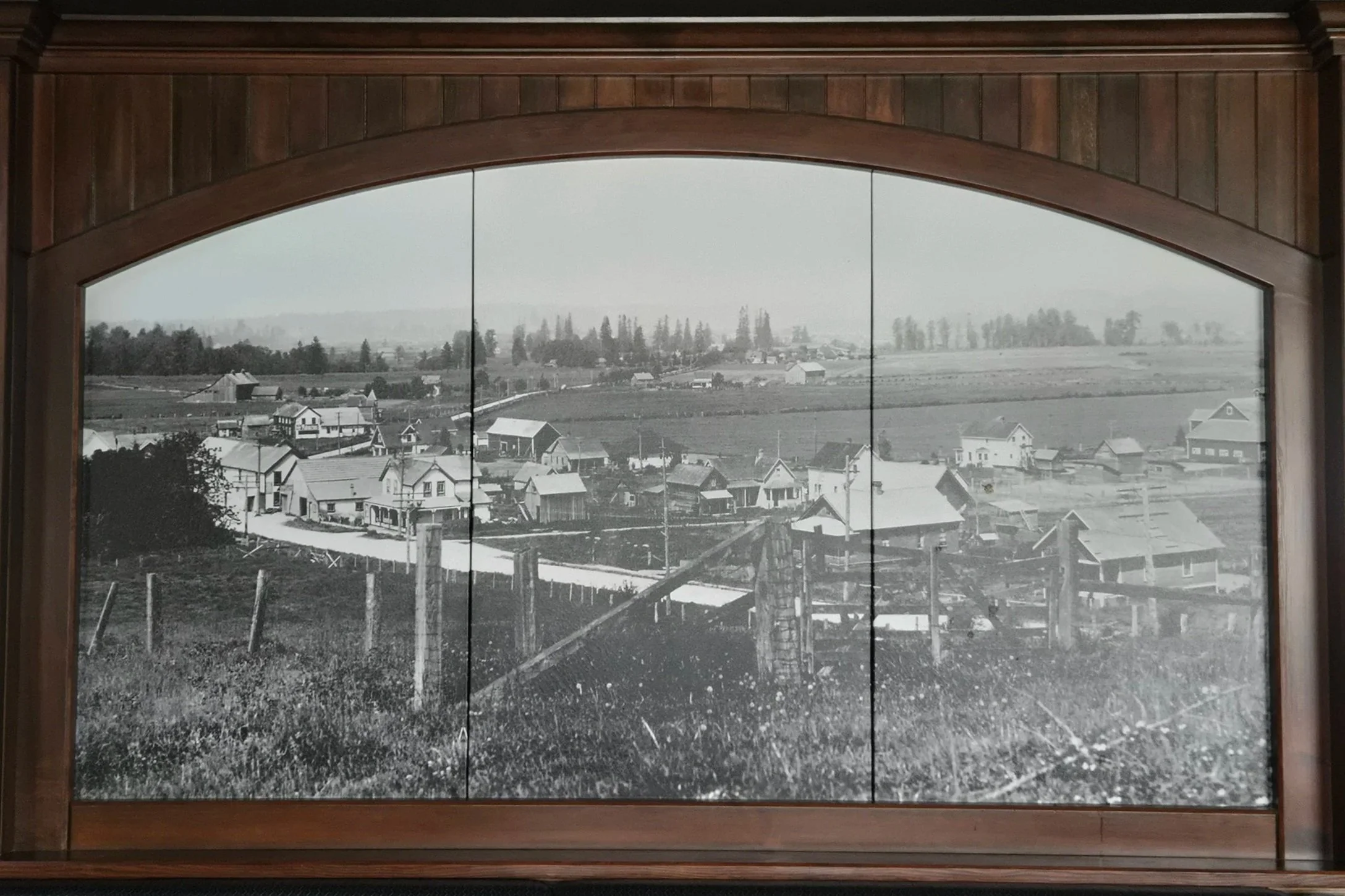 A black-and-white photo depicting the original Murrayville settlement! Complete with farm land and dusty roads, this shows an up and coming area surrounded by fields, and trees.
