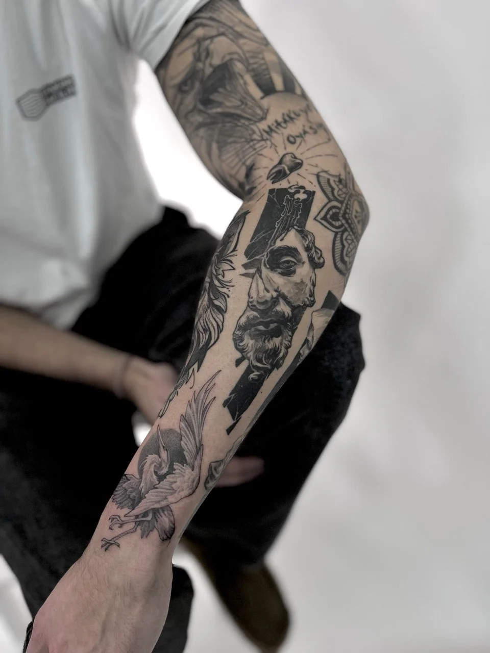 Close-up of a person's arm with various black ink tattoos by Dmytro Shcherbakov
