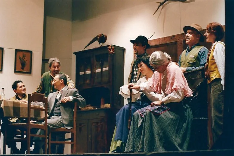 Attore e attrice in costume su un palco teatrale, con altri personaggi, durante una rappresentazione teatrale.