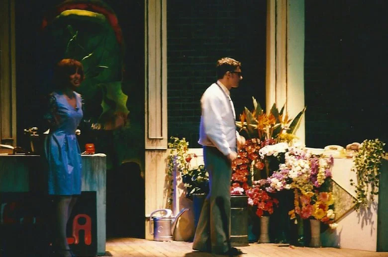 Coppia di persone, una donna e un uomo, in un ambiente decorato con molti fiori colorati.