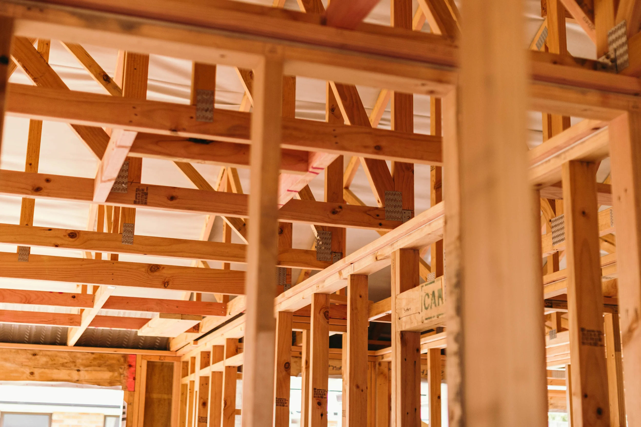 Wooden framing for a building under construction by Zephyr Construction with vertical and horizontal beams and metal brackets.