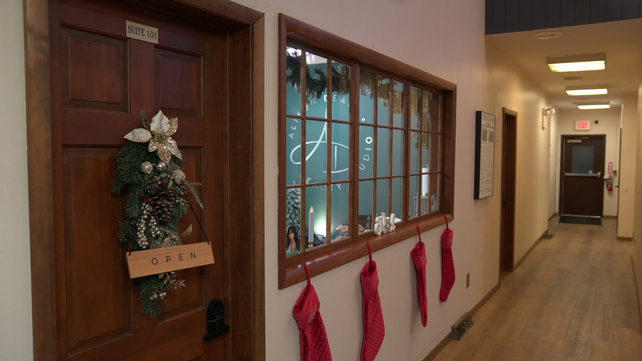 Hallway with decorated door, Christmas stockings hanging on the wall, and holiday decorations visible through the window.