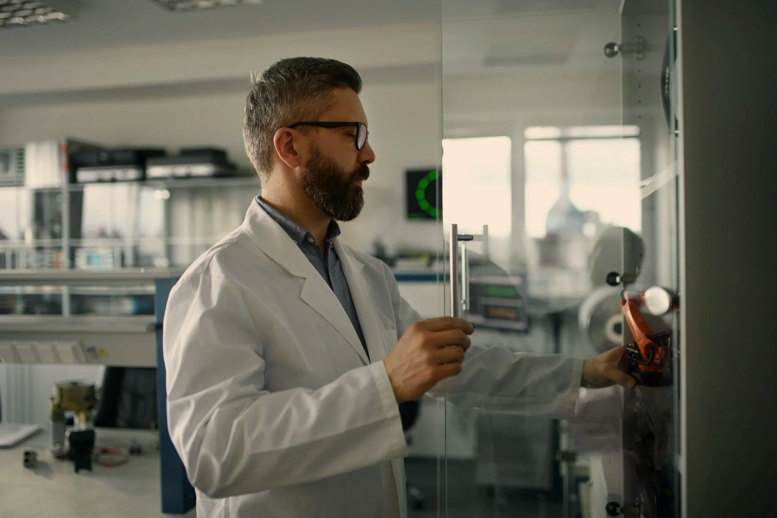 A male scientist or engineer in a white lab coat working with scientific equipment in a laboratory.