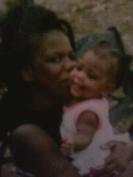 A woman holding a smiling baby girl in a stroller