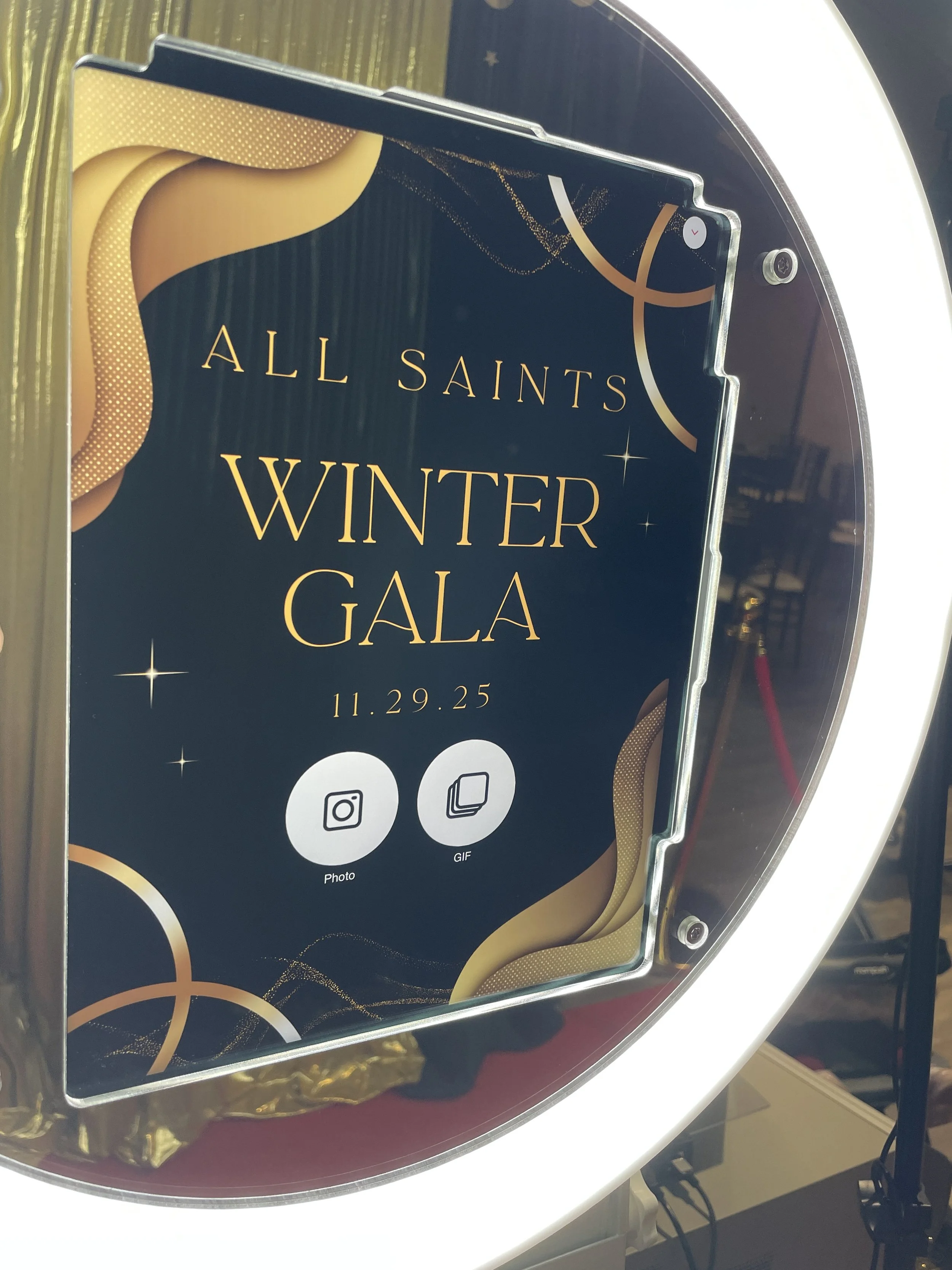 Event poster for the All Saints Winter Gala on November 29, 2025, displayed on a mirror or reflective surface with icons for sharing photos and GIFs.