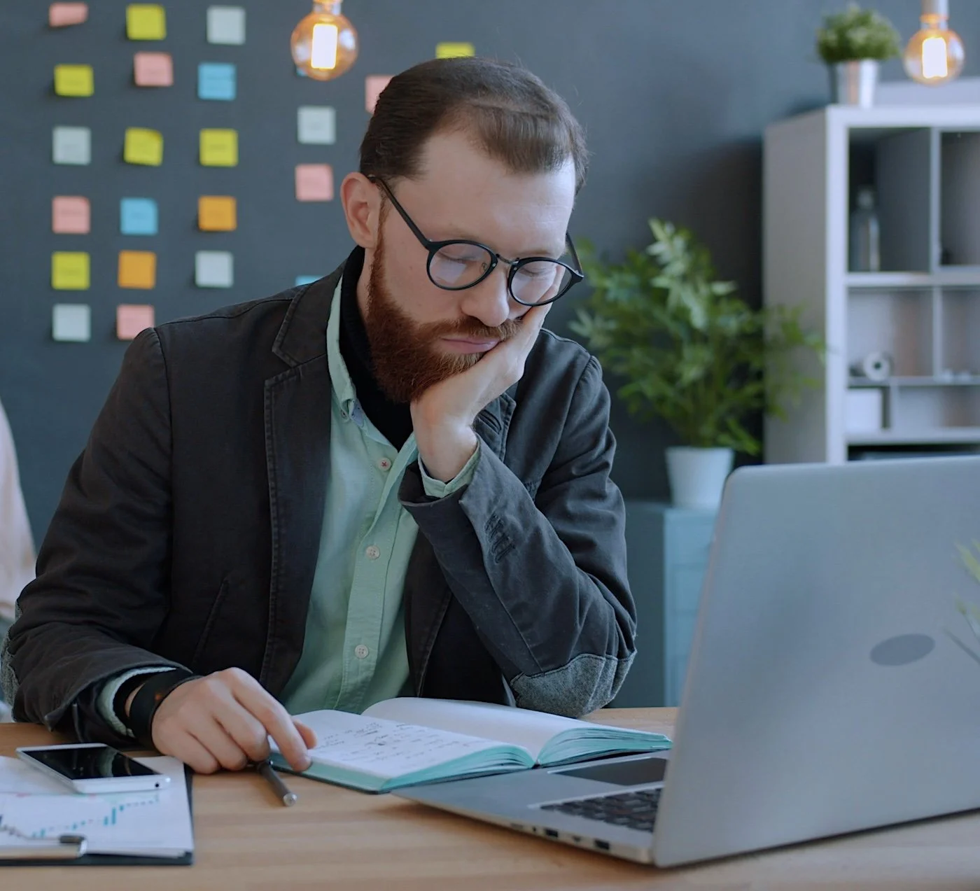 Stresses business executive sitting at a desk with a notepad and laptop