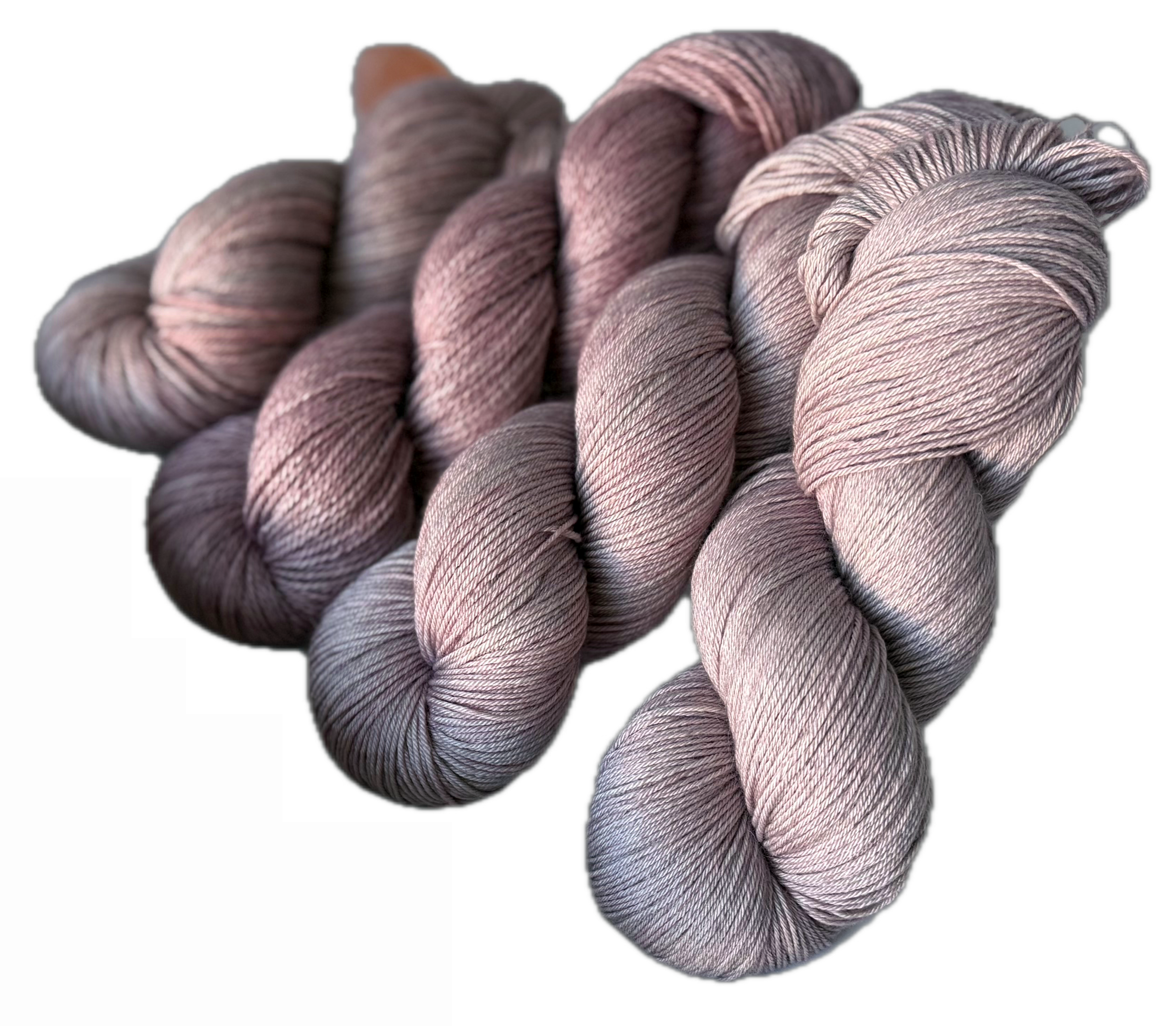 Three skeins of pink and gray variegated yarn twisted into hanks.