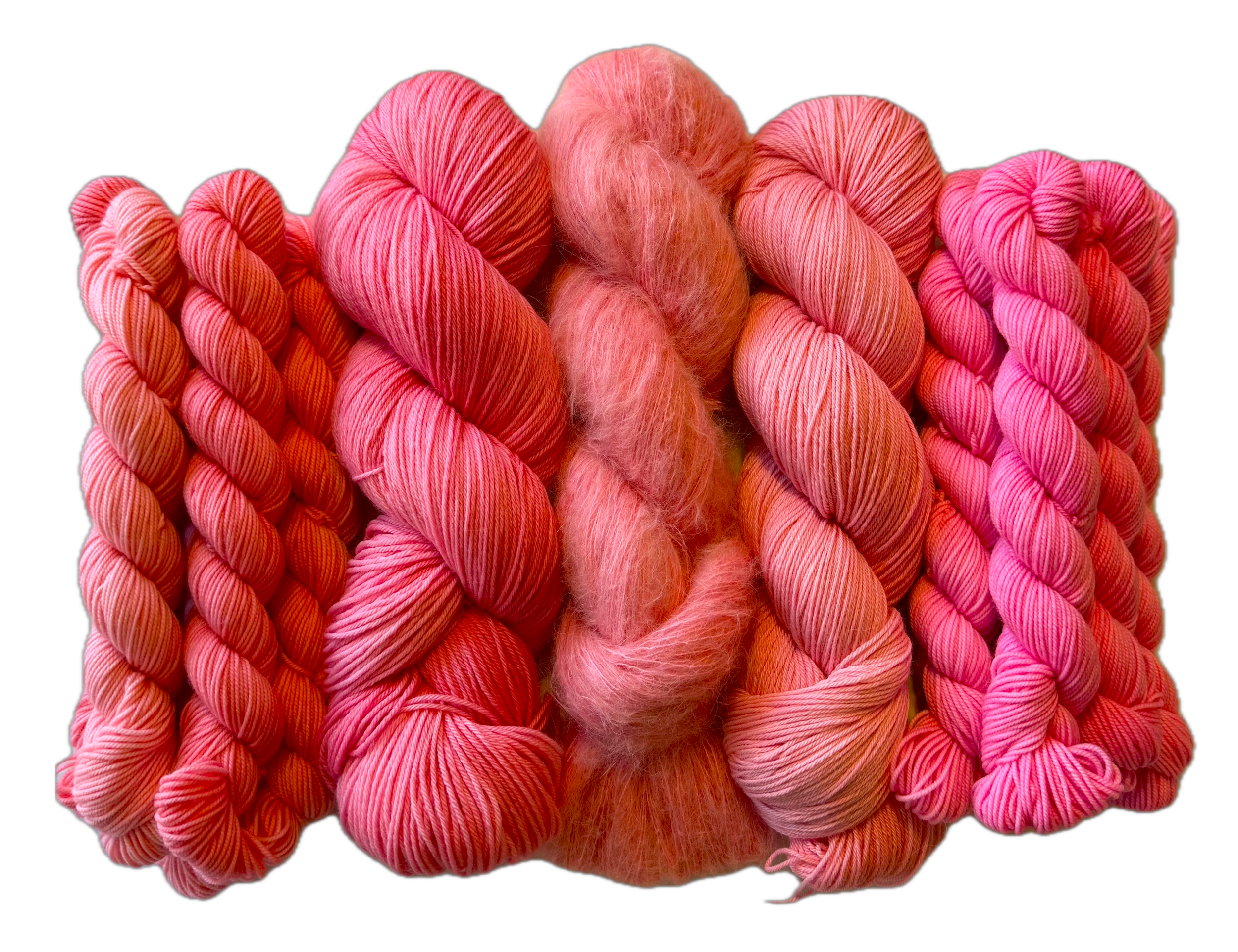 Assorted pink and peach hand dyed yarn skeins arranged together.