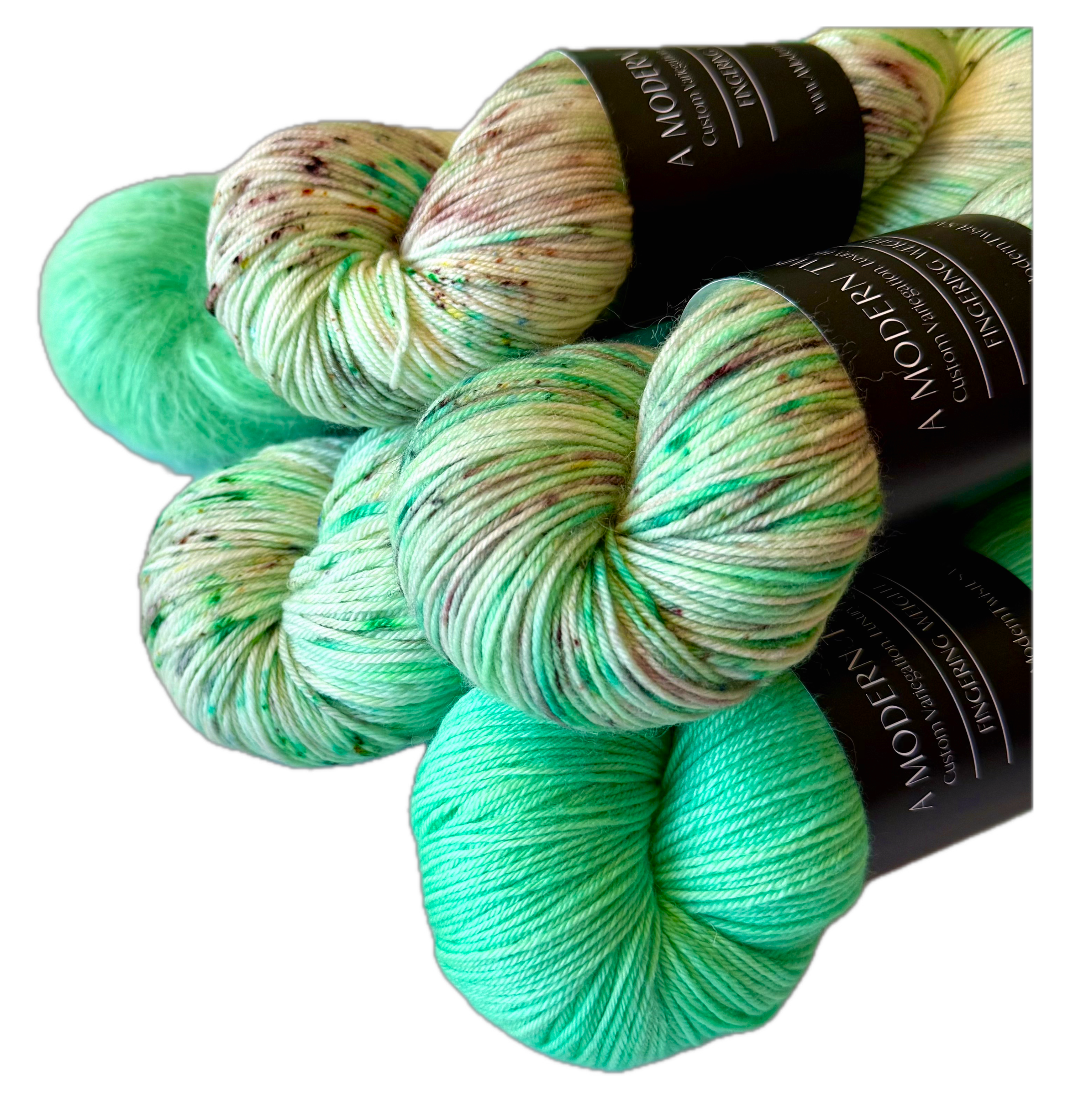 Four skeins of colorful yarn hand dyed in shades of white, green, and speckled patterns.