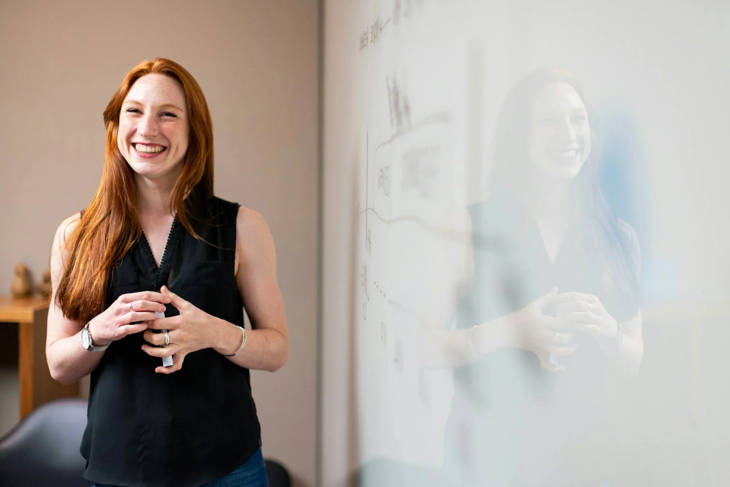 A young Marketing Specialist standing next to a whiteboard in an office or agency setting.