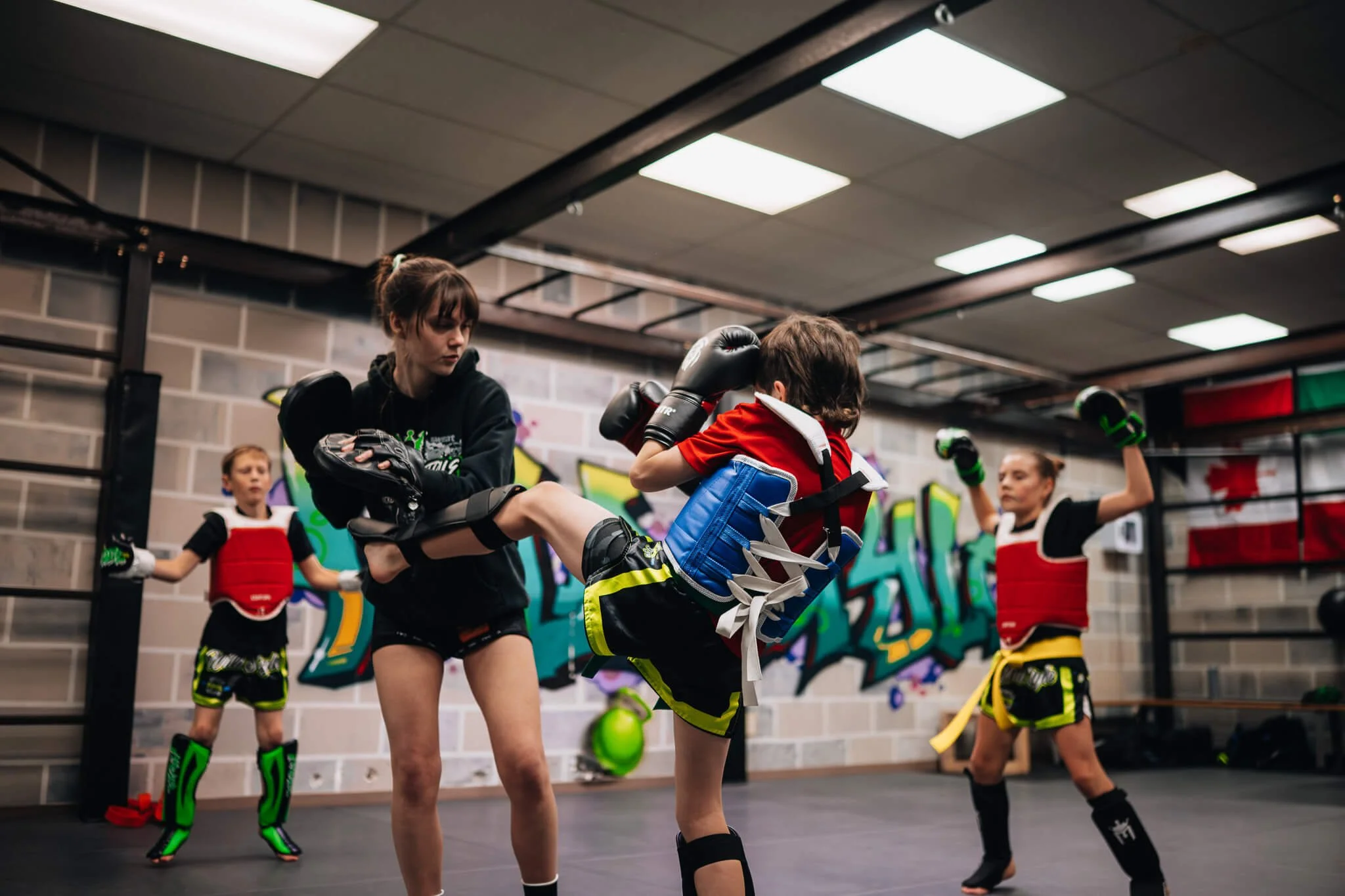 Kids kickboxing class at WildStyle Gym in Snohomish, WA, with young athletes practicing kicks and pad work under coach supervision.