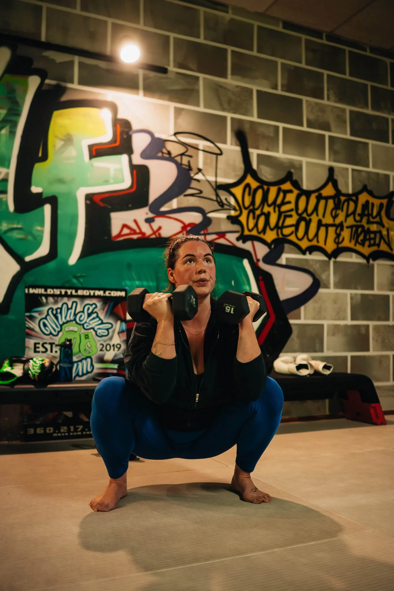 A WildStyle Gym member performs a deep squat with dumbbells during a Champ Camp training session in Snohomish, Washington, building functional strength, mobility, and confidence in a coached small-group fitness environment.