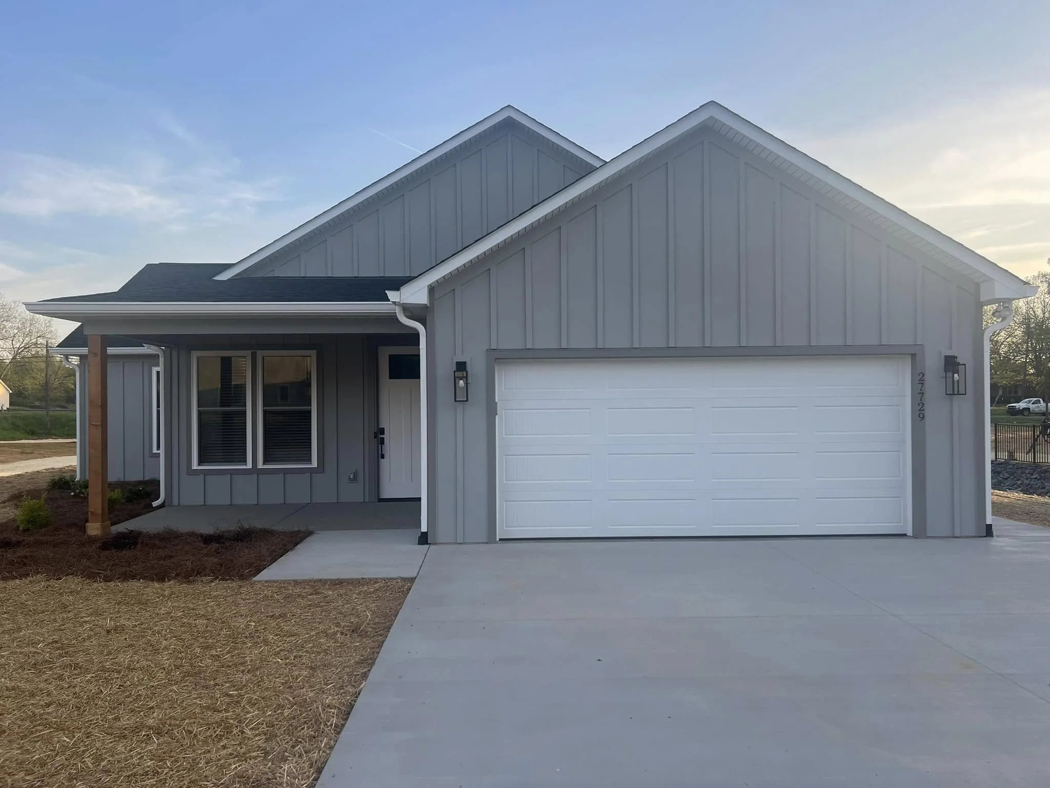 Front view of a modern gray house with a two-car garage, small porch, and a lawn area under construction.