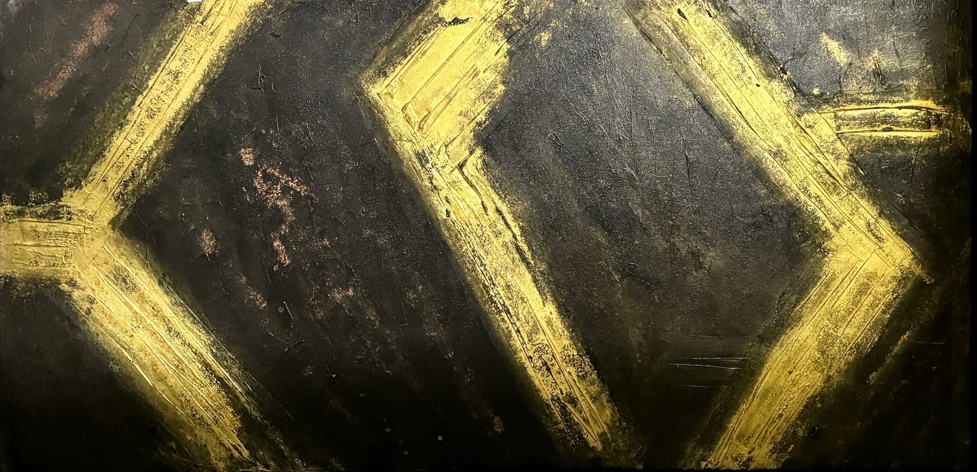 Close-up of a dark textured surface with gold geometric lines and accents forming a pattern.