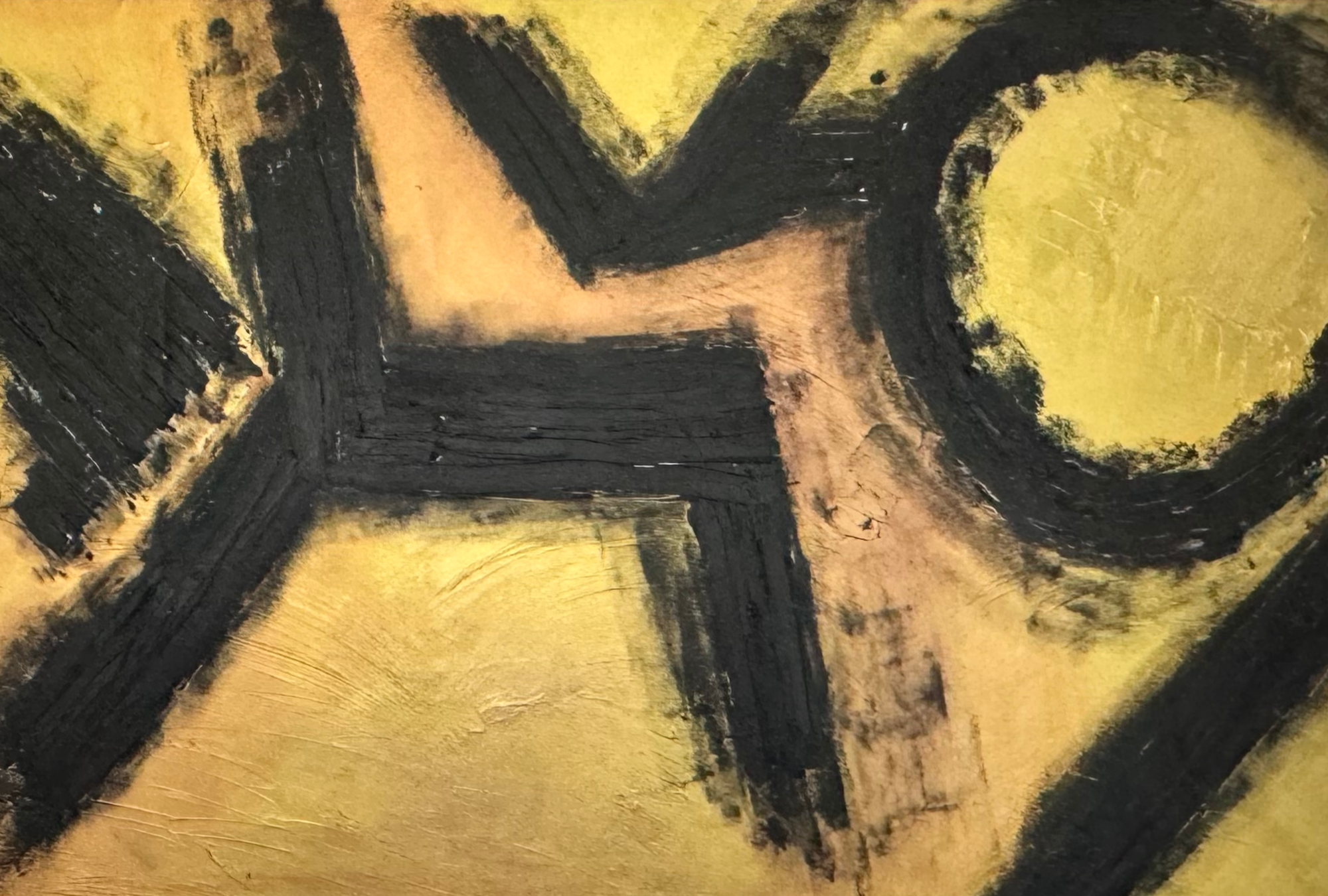Close-up of an abstract painting with black brushstrokes on a textured gold and black background.