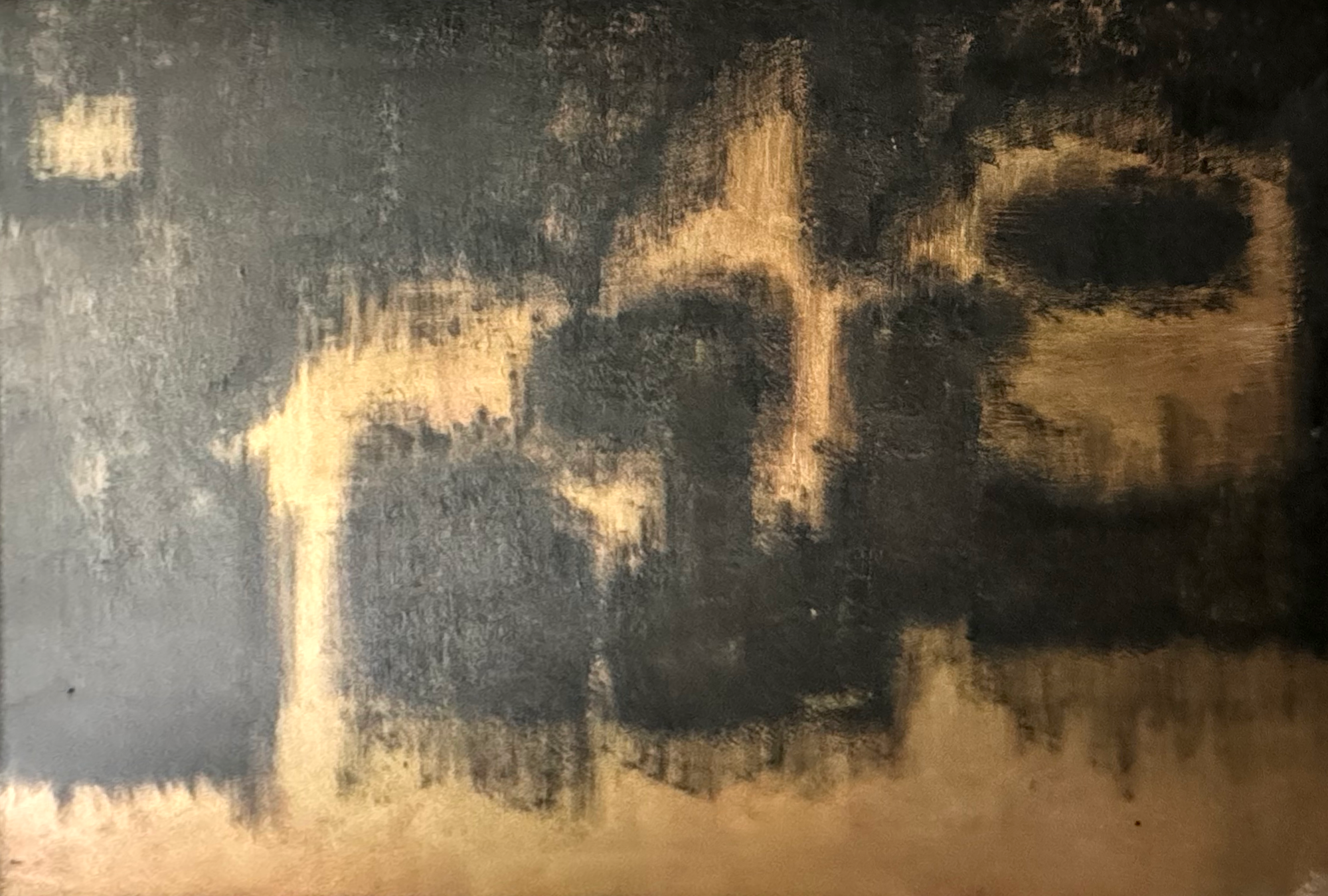 Close-up of a dark, textured surface with a pattern resembling a human face, created by lighter and darker areas.