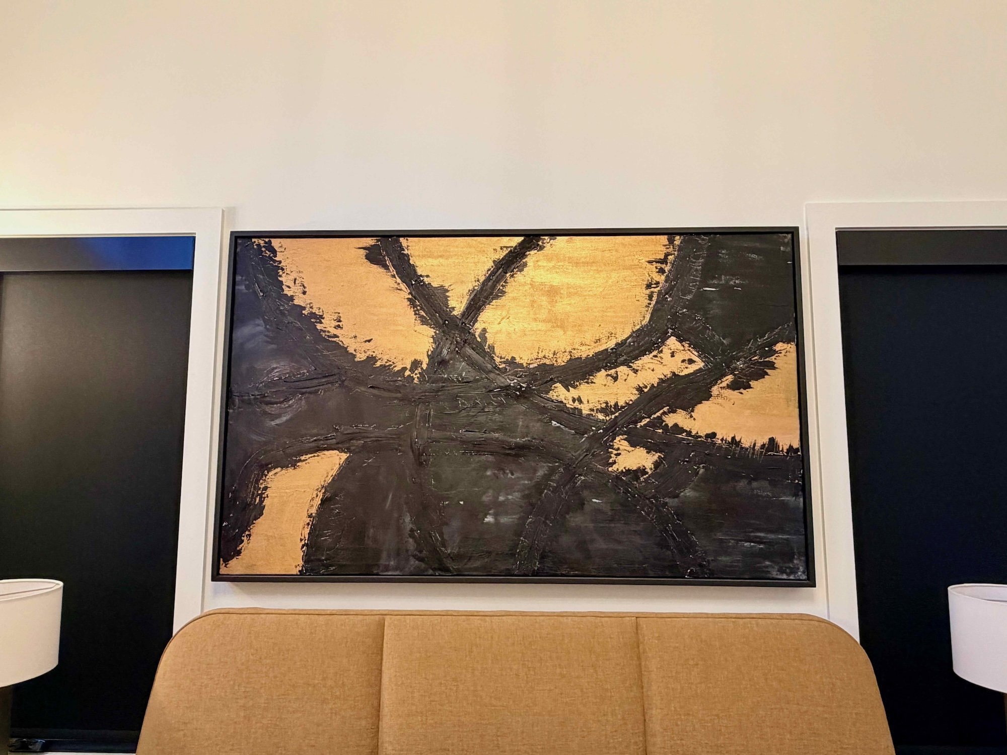 Contemporary abstract painting with black and gold brushstrokes on a rectangular canvas.