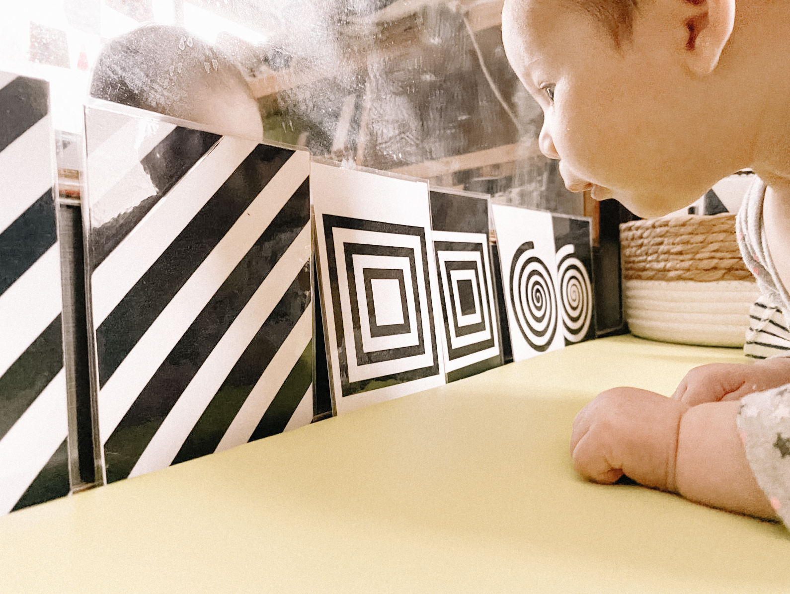 Un jeune enfant regarde un panneau avec des motifs géométriques en noir et blanc, dont des carrés et des spirales.