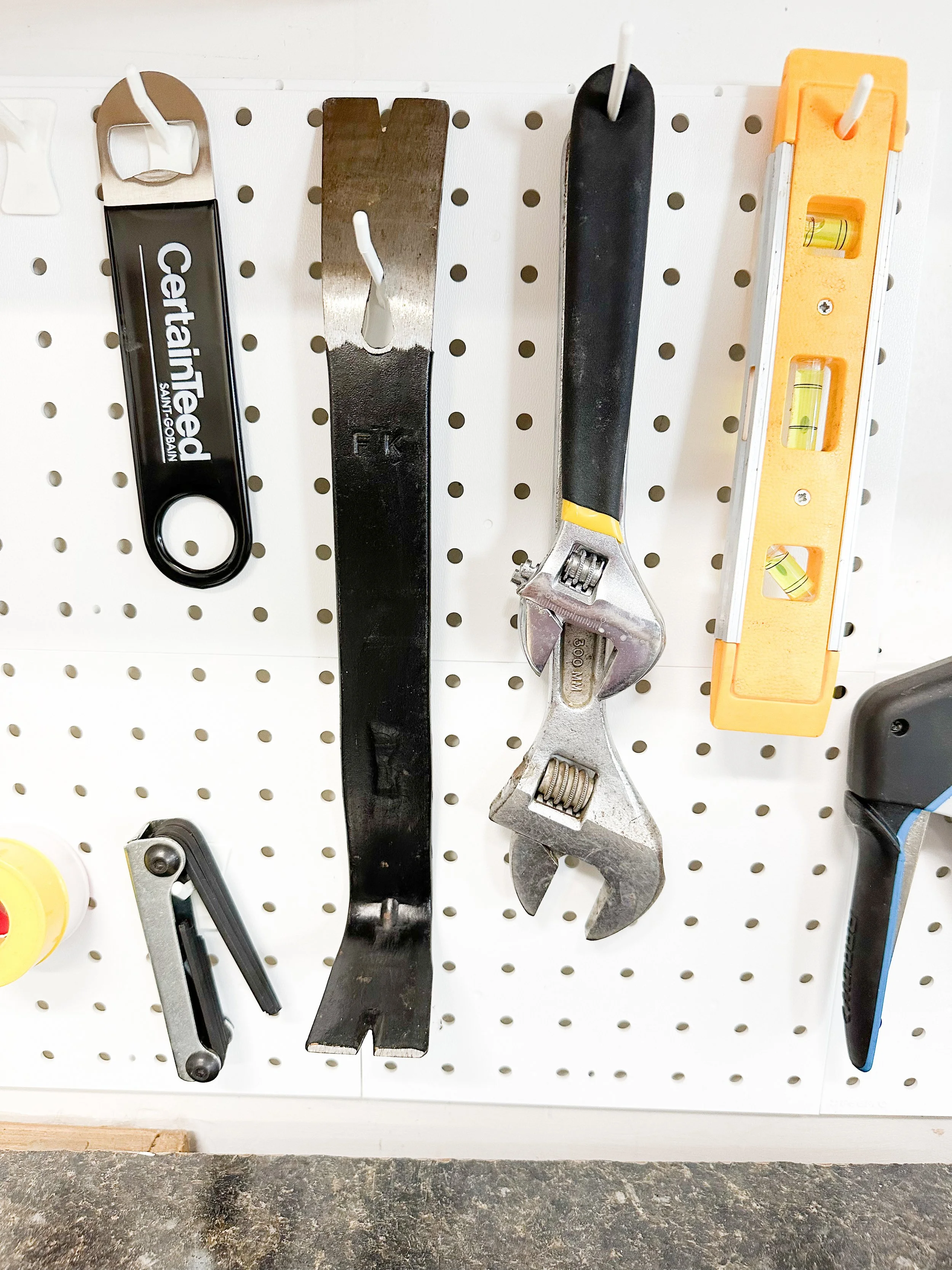 Tools hanging on a pegboard, including a wrench, adjustable wrench, a level, and other tools.