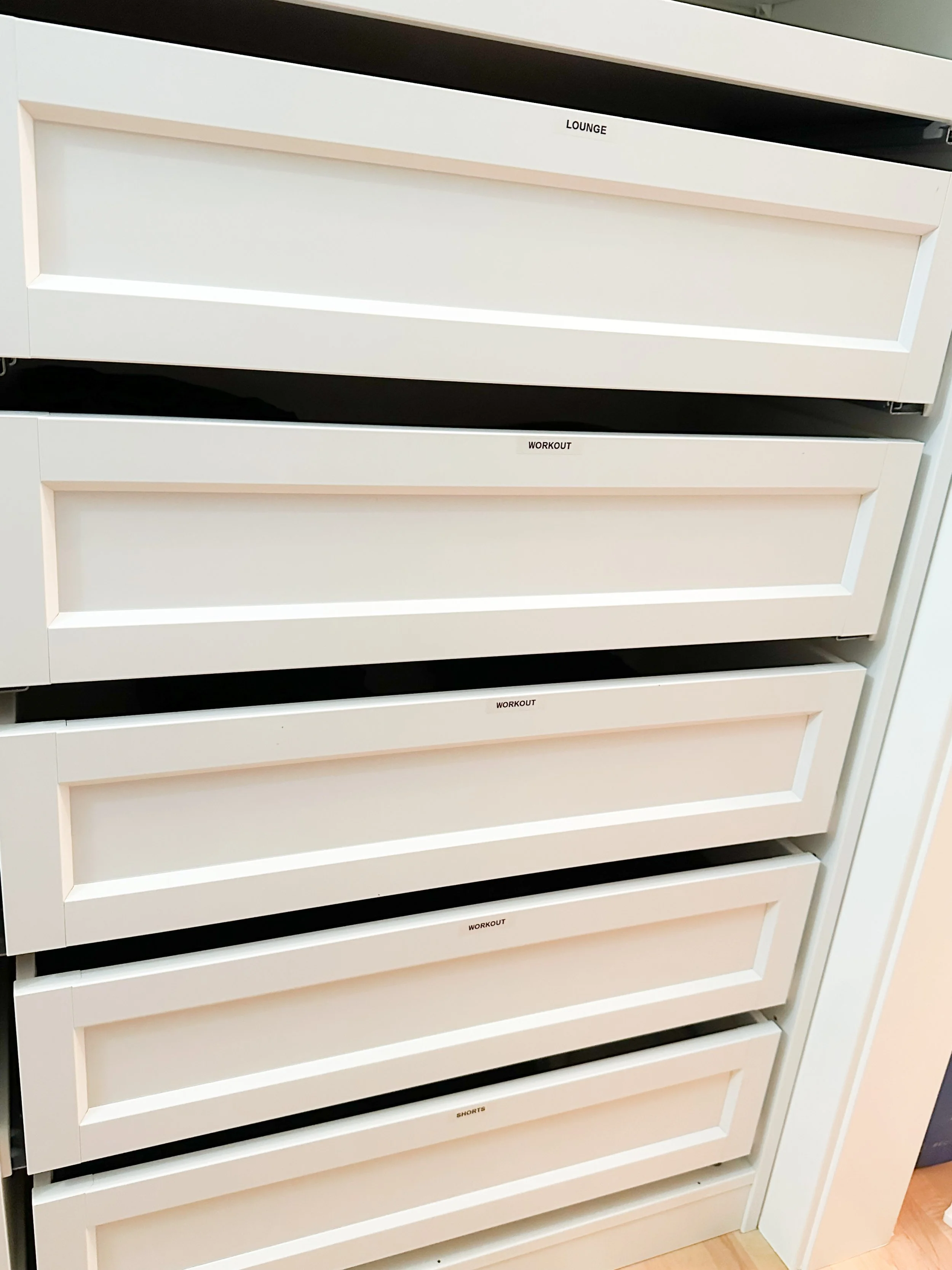 White dresser with multiple labeled drawers for lounge, workout, and shorts.