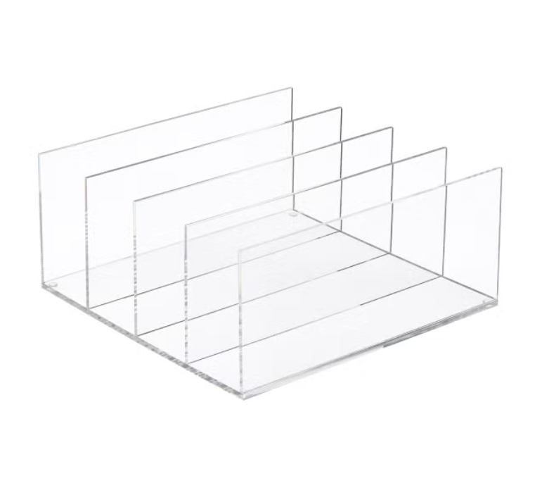 A clear acrylic countertop organizer with five vertical compartments of varying heights.