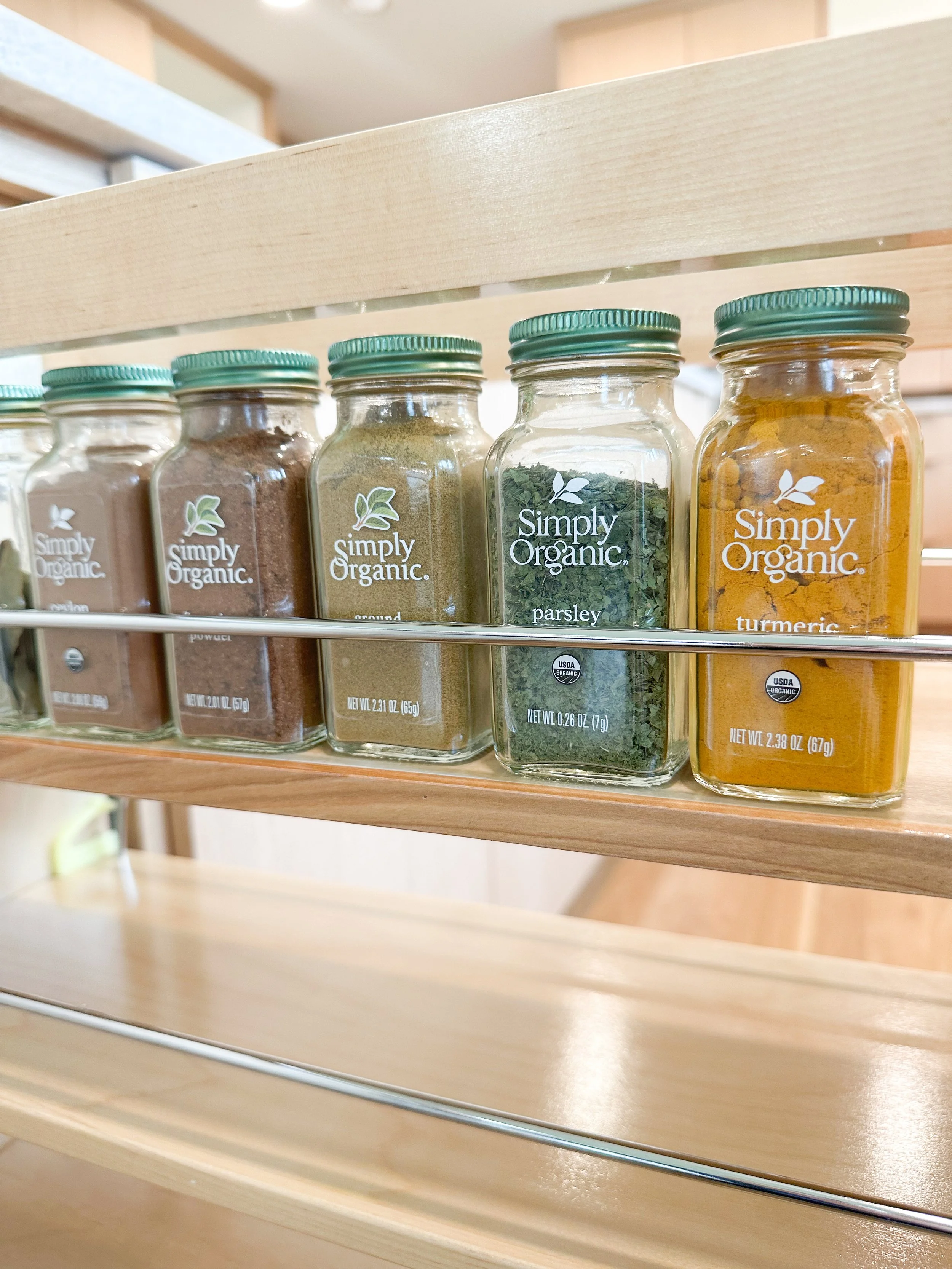 Close-up of a spice rack with jars of organic spices including turmeric, parsley, and various ground spices.