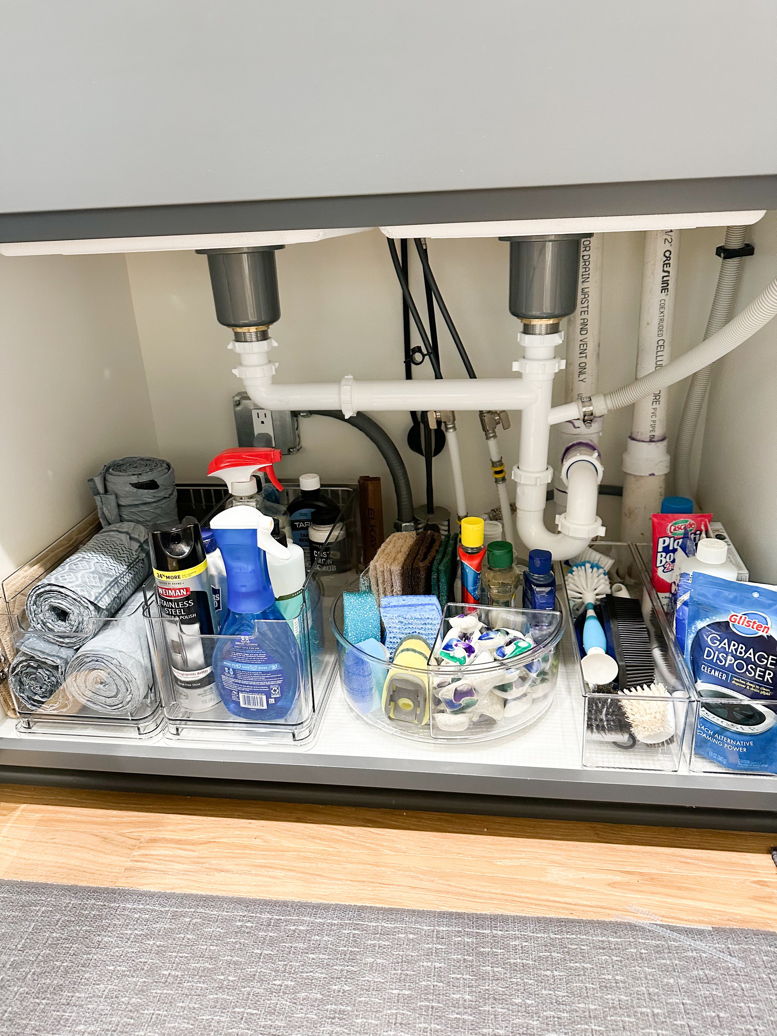 Under-sink cleaning supplies and tools organized in clear containers.