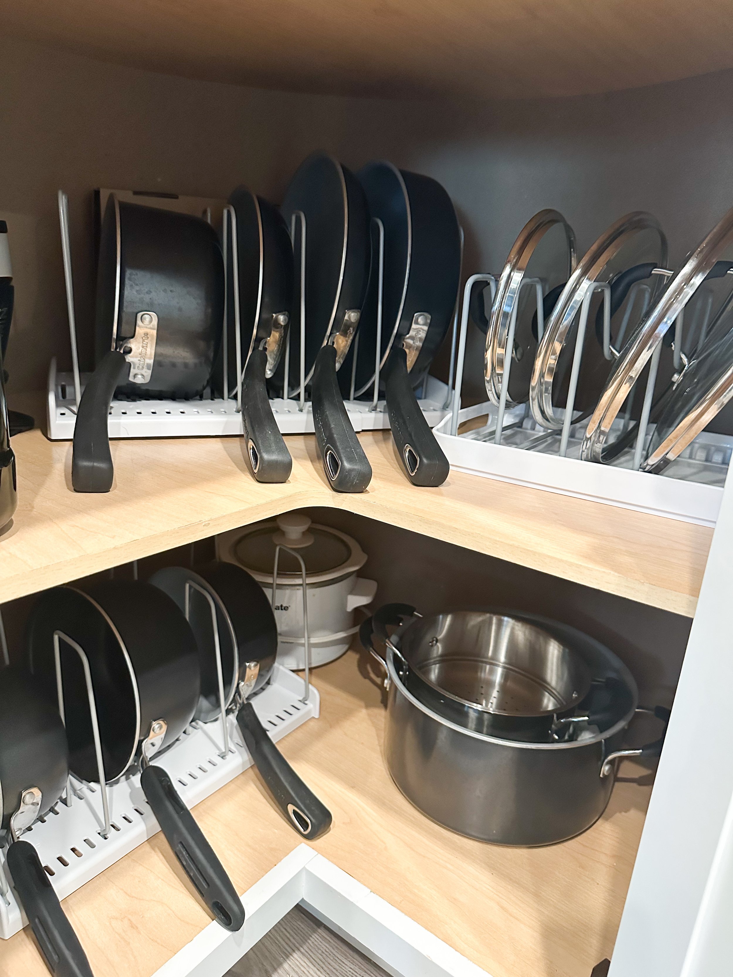 Organized kitchen pots and pans stored on shelves with utensils and cookware.