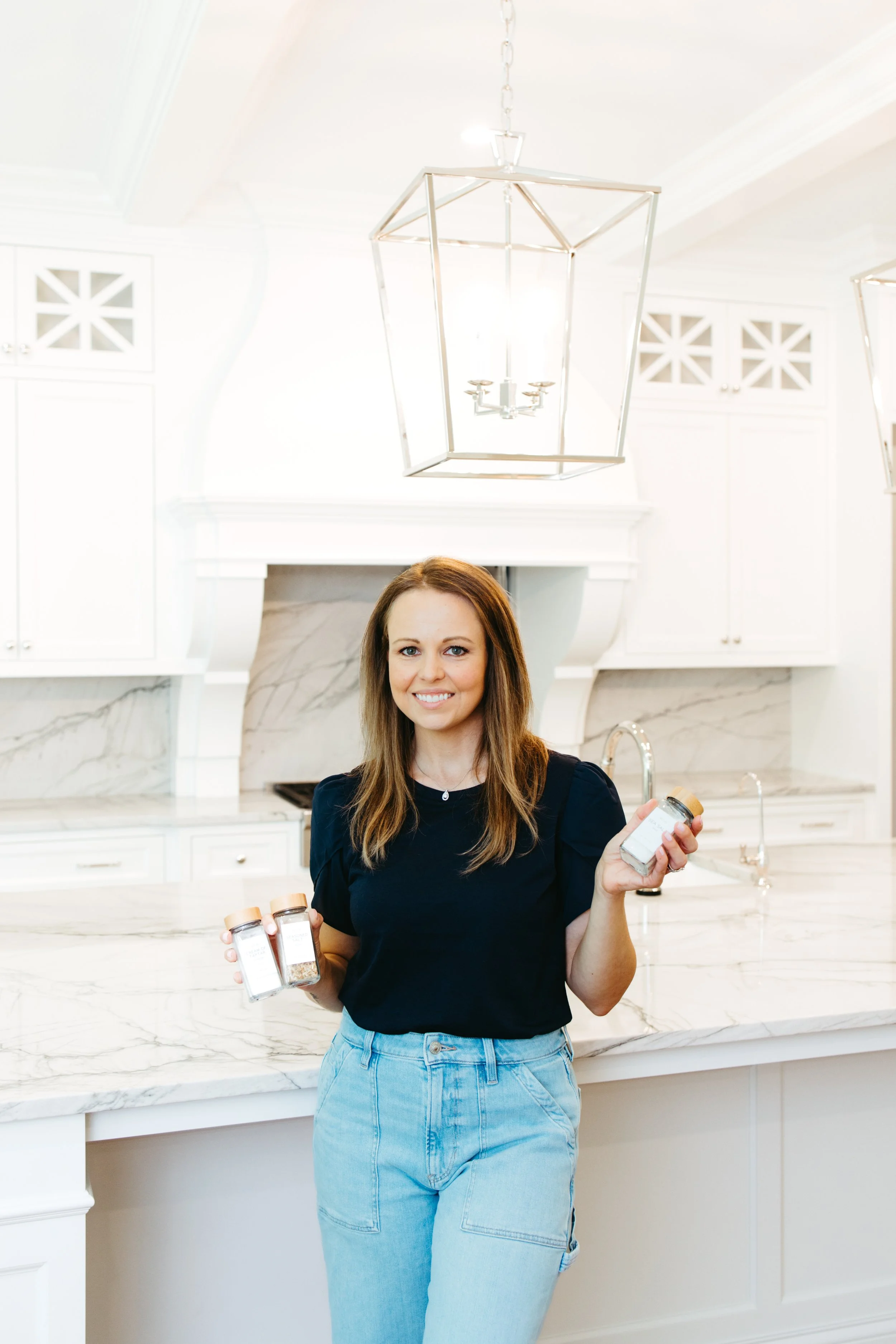 Woman smiling in modern kitchen holding spice jars