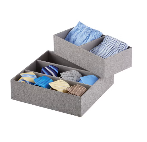 Two grey fabric storage boxes containing neatly folded men's dress shirts and neckties.