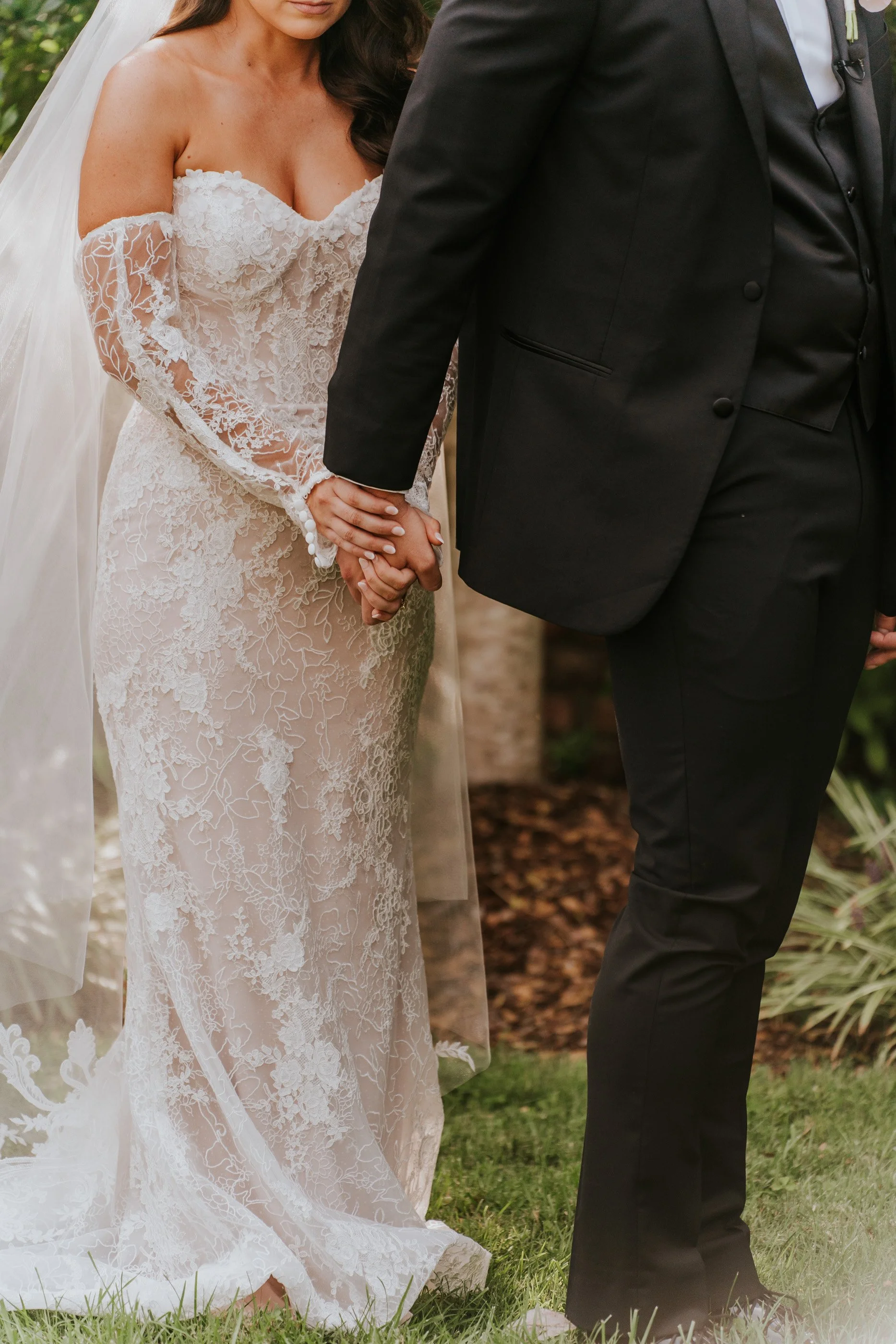 A bride and groom holding hands during their wedding ceremony outdoors.