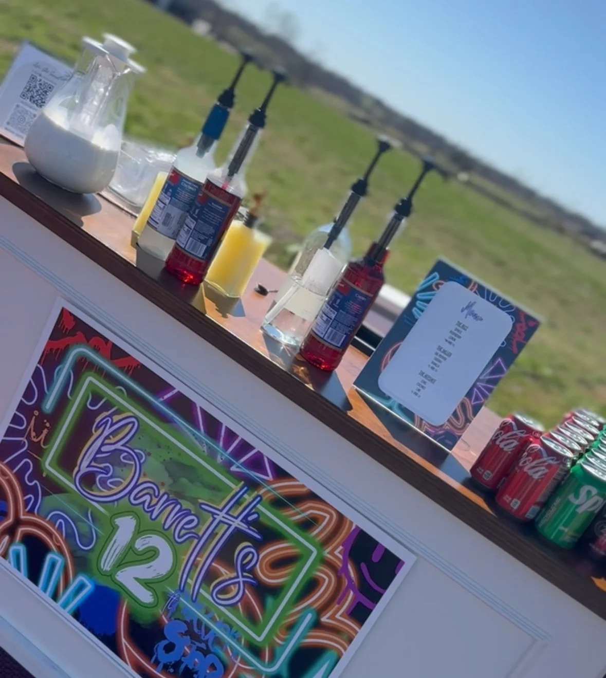 Colorful neon sign with the text "12" and additional text that is partially obscured, advertising a sale or special event at a carnival or fair.