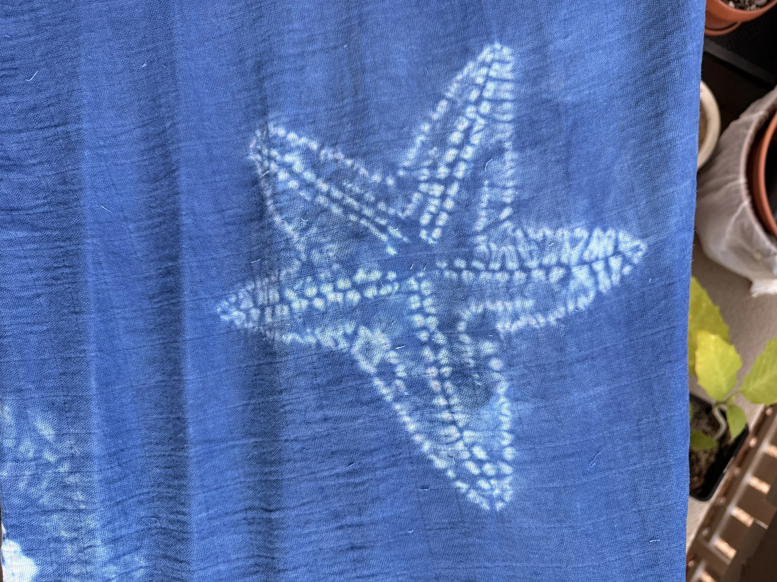 Closer look at a starfish.  Blue fabric, with white, splotchy lines that form an image of a starfish.