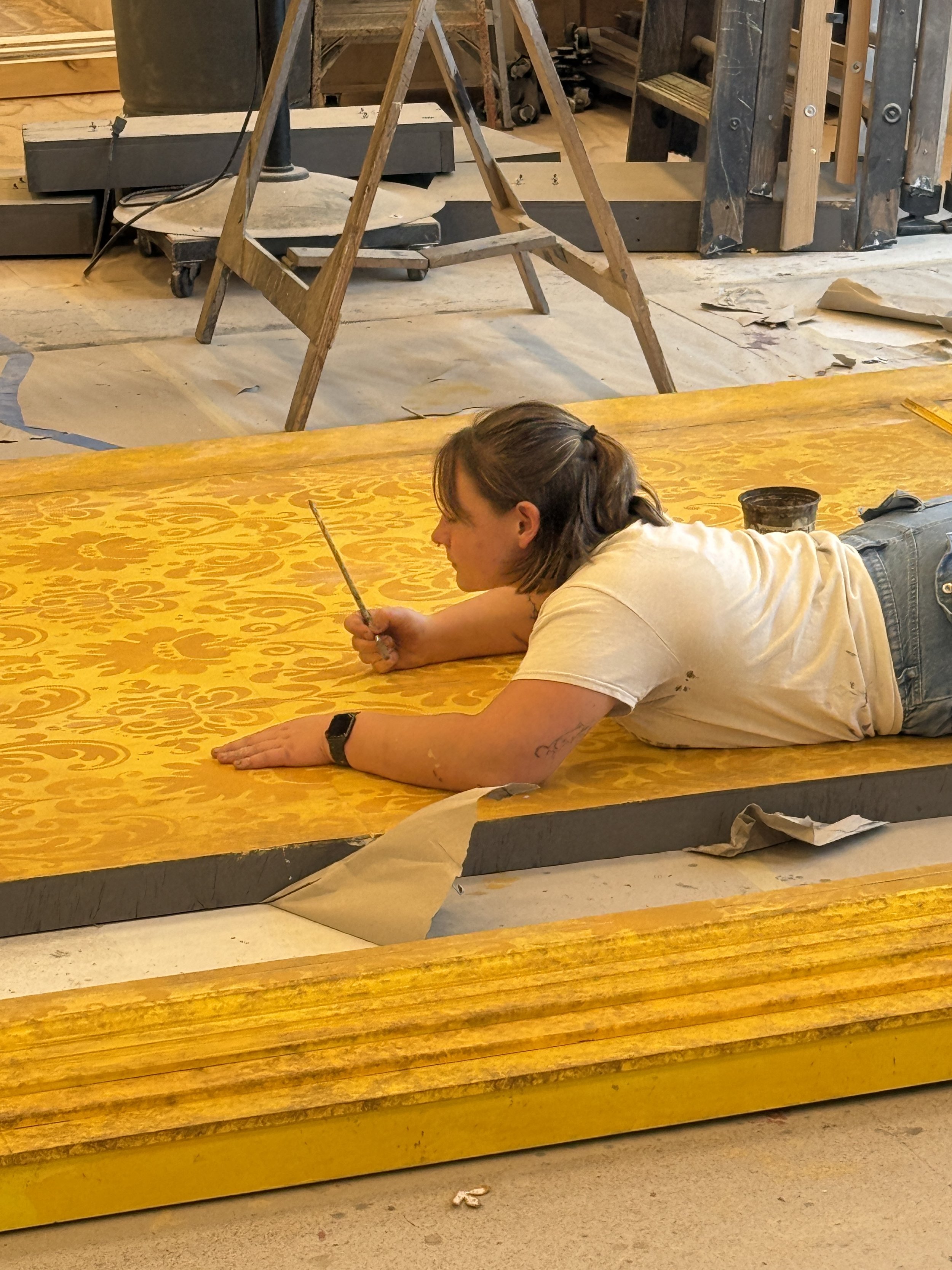 Goldie Snow touching up hand stenciled wallpaper pattern