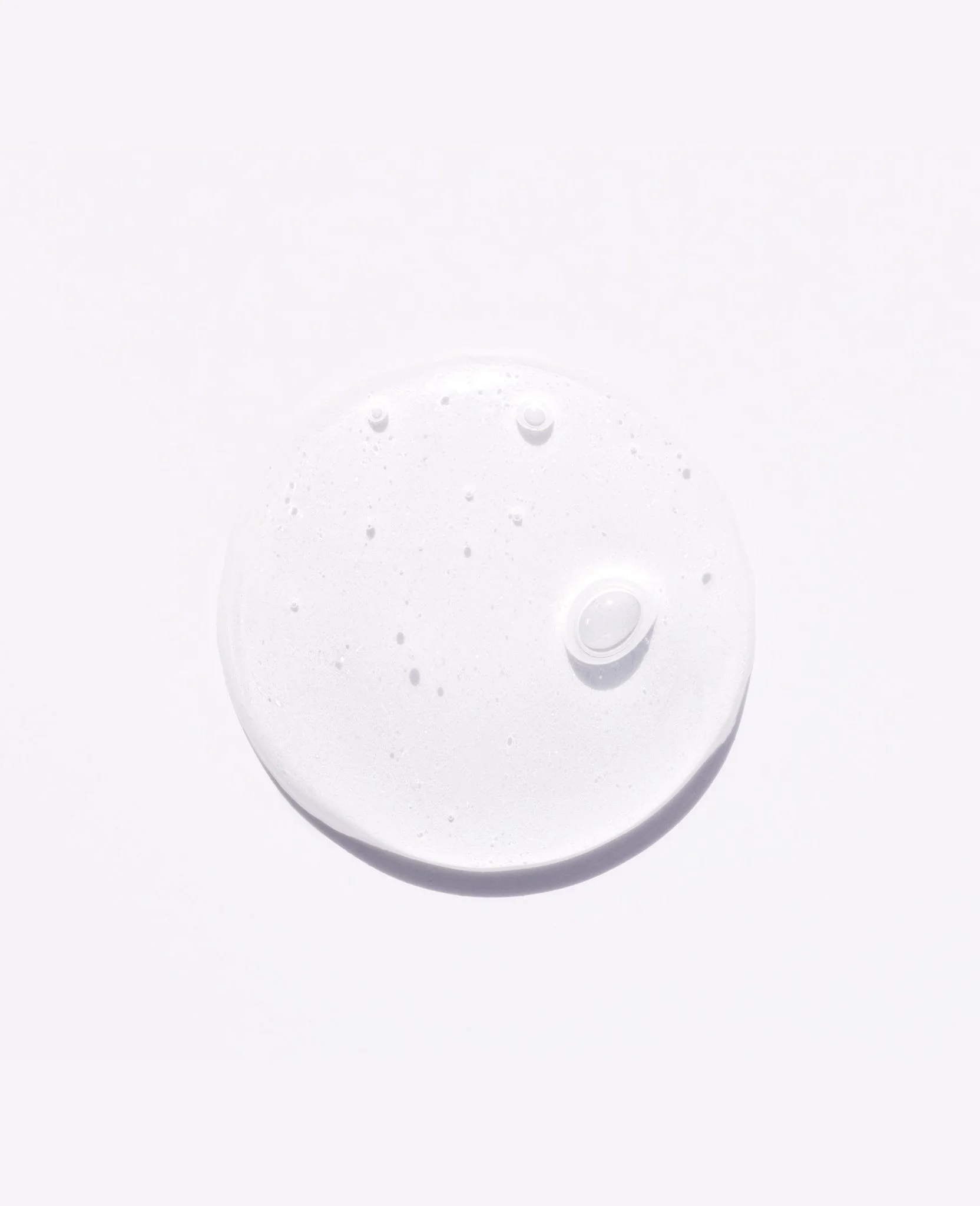 Close-up of a clear, bubbly soap or liquid droplet on a white surface.