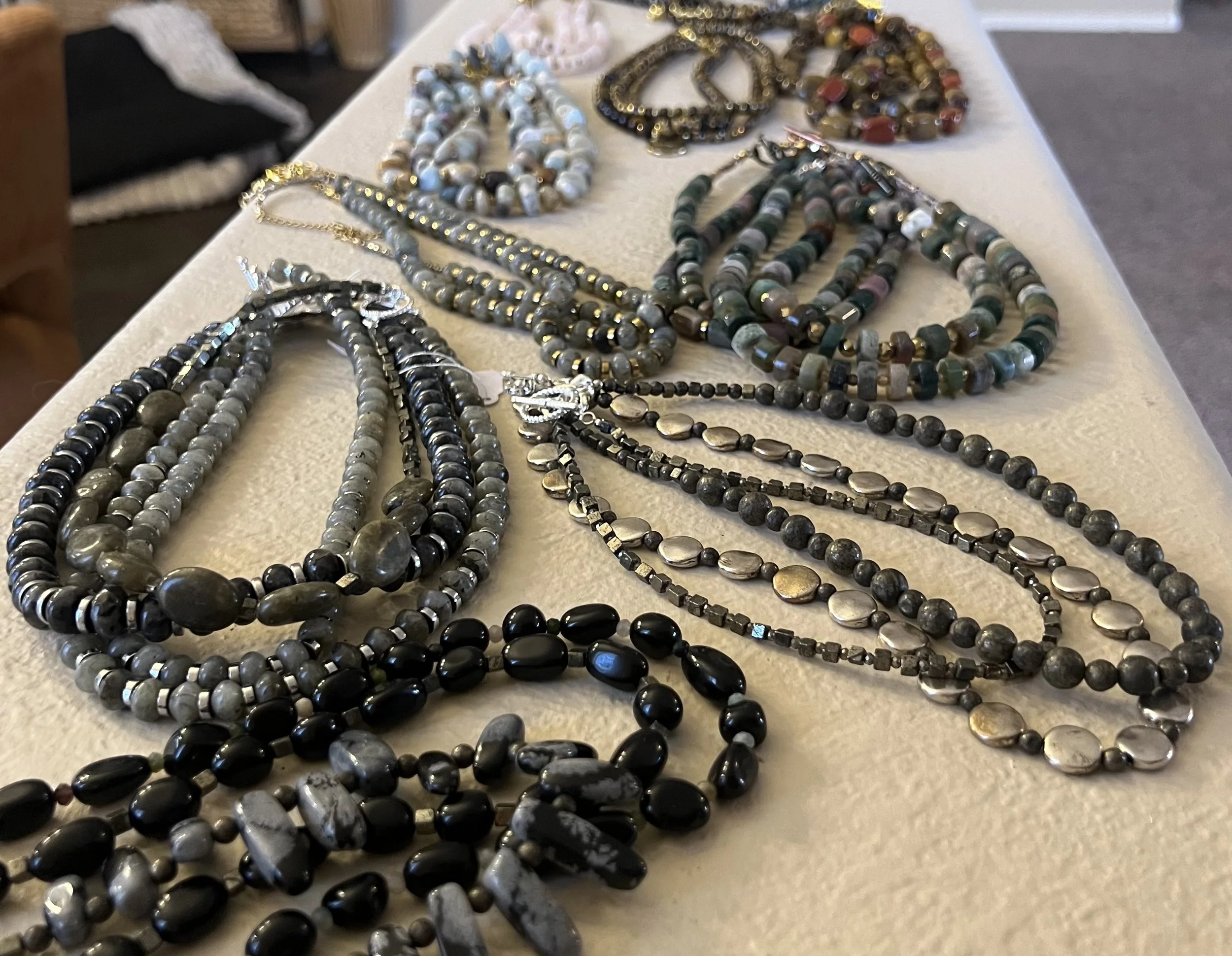 Various beaded necklaces displayed on a light-colored table.