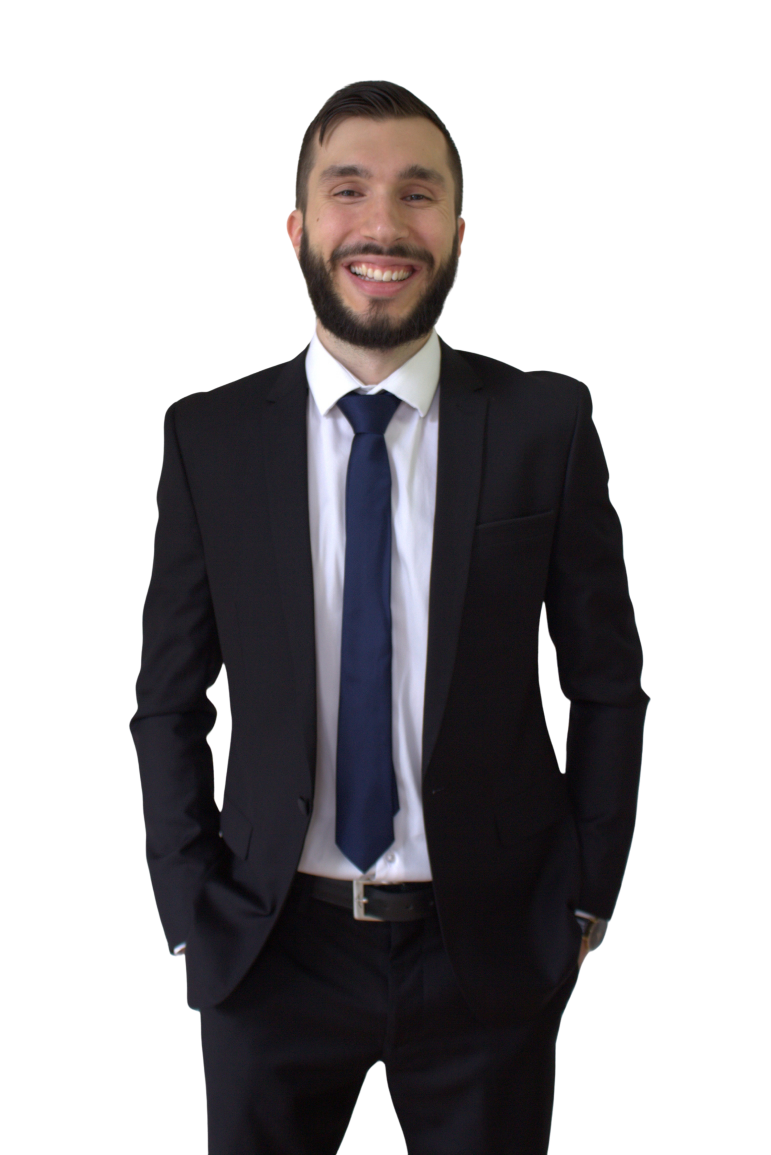 A smiling man in a black suit, white shirt, and blue tie, standing with hands in pockets.