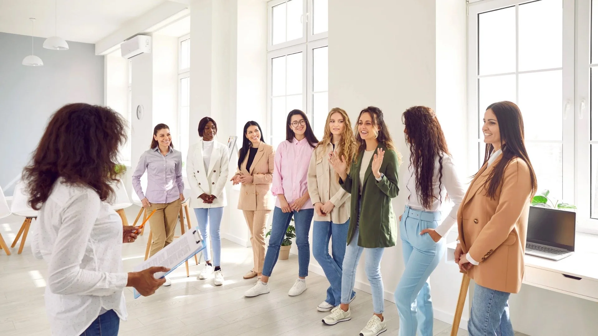 Group of women participating in a discussion or presentation in a bright, modern office space.