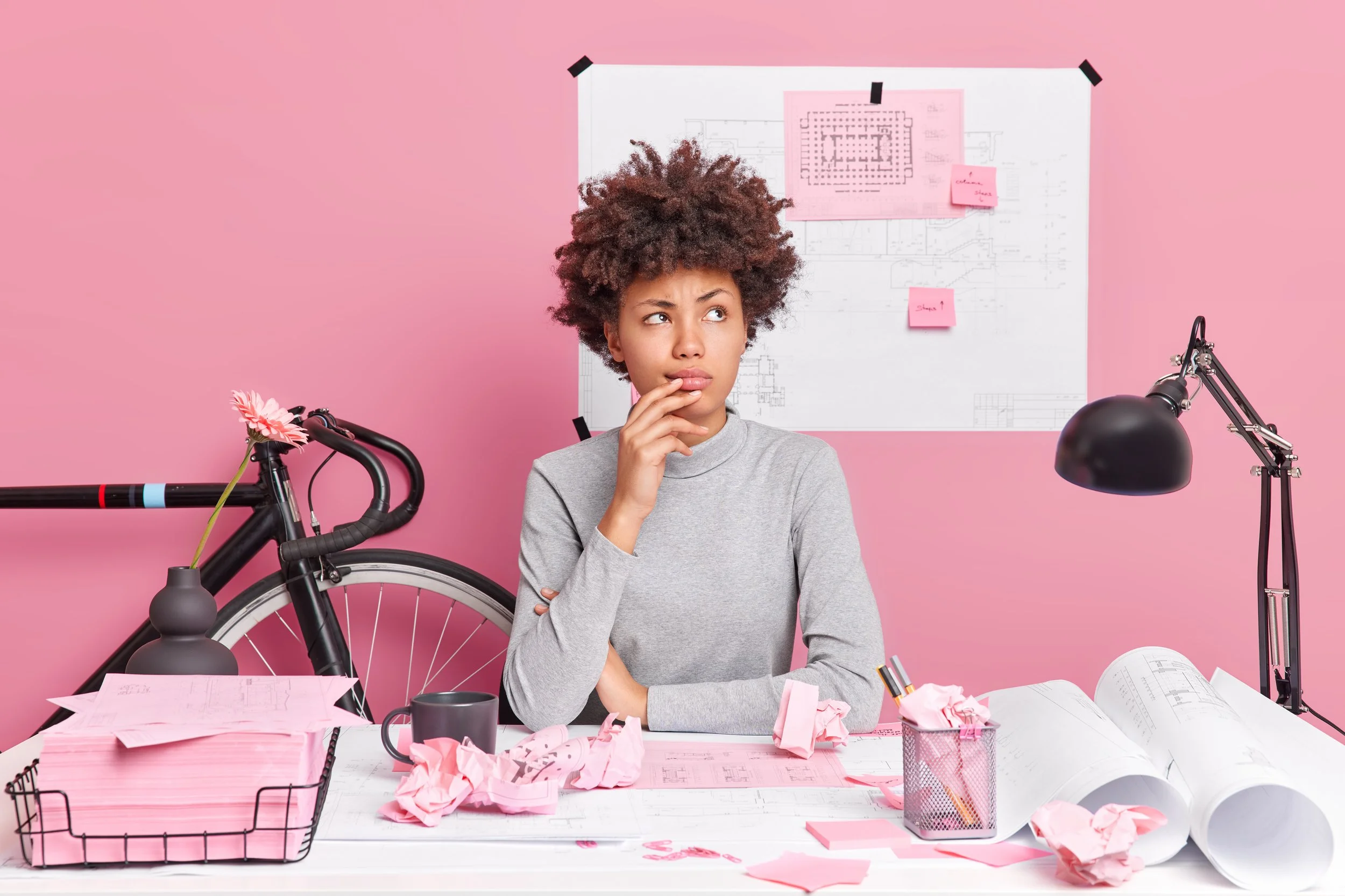 horizontal-shot-thoughtful-afro-american-woman-poses-coworking-space-has-pensive-expression-makes-architectural-project-draws-sketches-designing-new-building-makes-plannings-assumptions