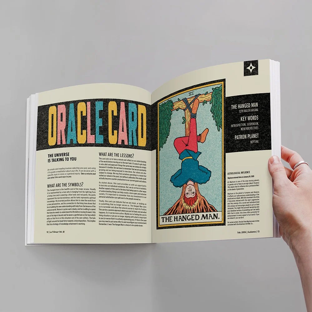 Open book showing tarot card titled 'The Hanged Man' with cartoon-style illustration of a person hanging upside down from a tree, with red hair and colorful clothing. The opposite page has text and colorful headings about oracle cards.