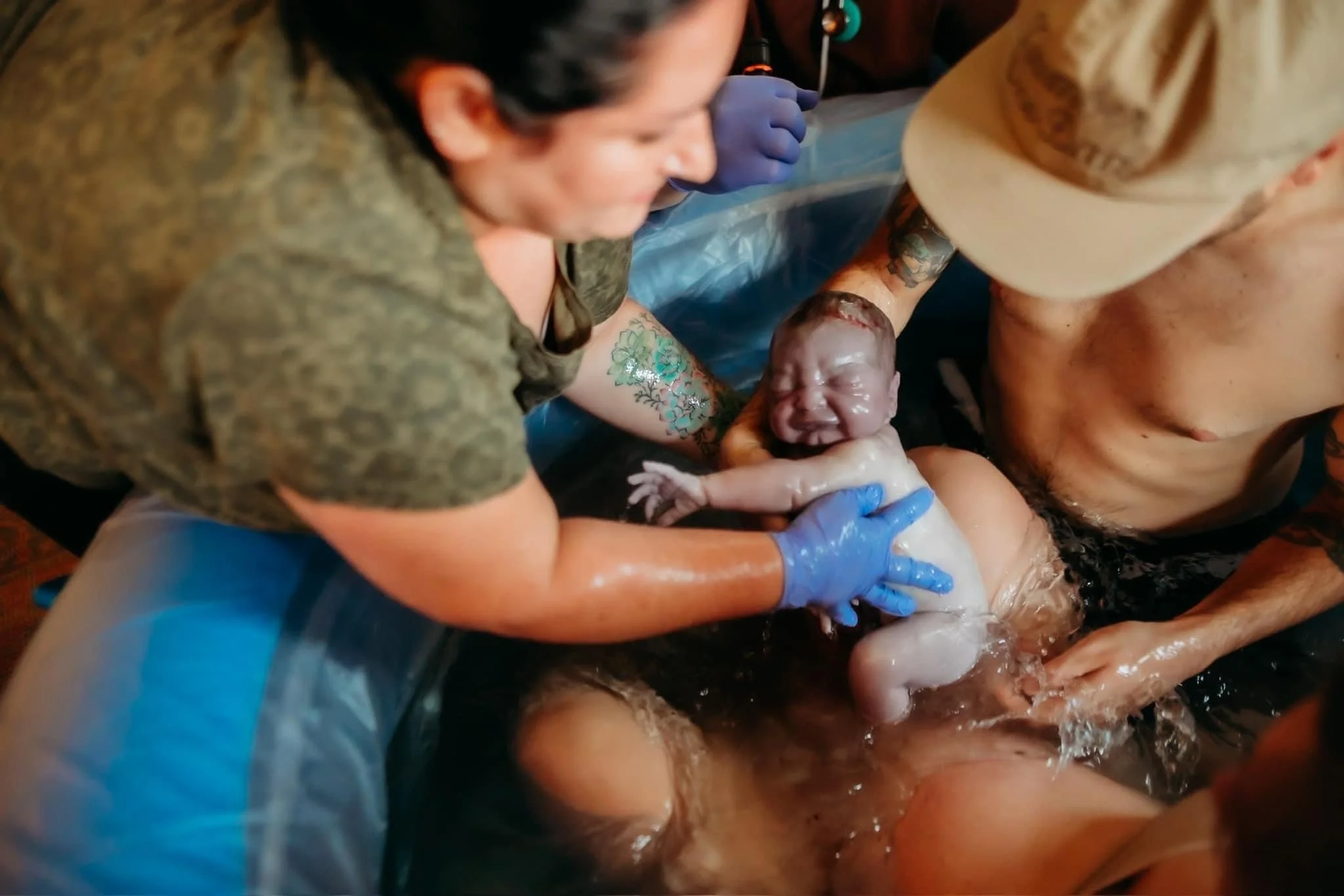 midwife catching baby coming out of water