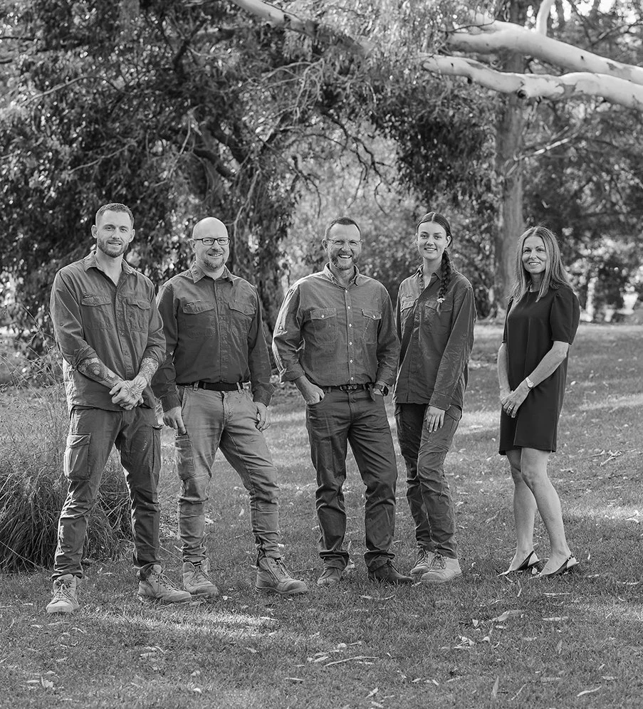 Ray Pollard and four staff members standing outdoors in a park, smiling for the camera, with trees and grass in the background, in black and white.