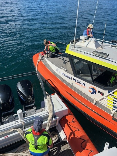 Marine rescue boat with rescue personnel handling a rescue operation on calm water.