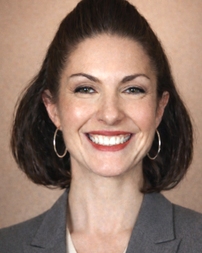 Tia Piacquadio, licensed independent counselor, headshot, smiling with brown hair, wearing hoop earrings and a gray blazer, standing against a brown background.