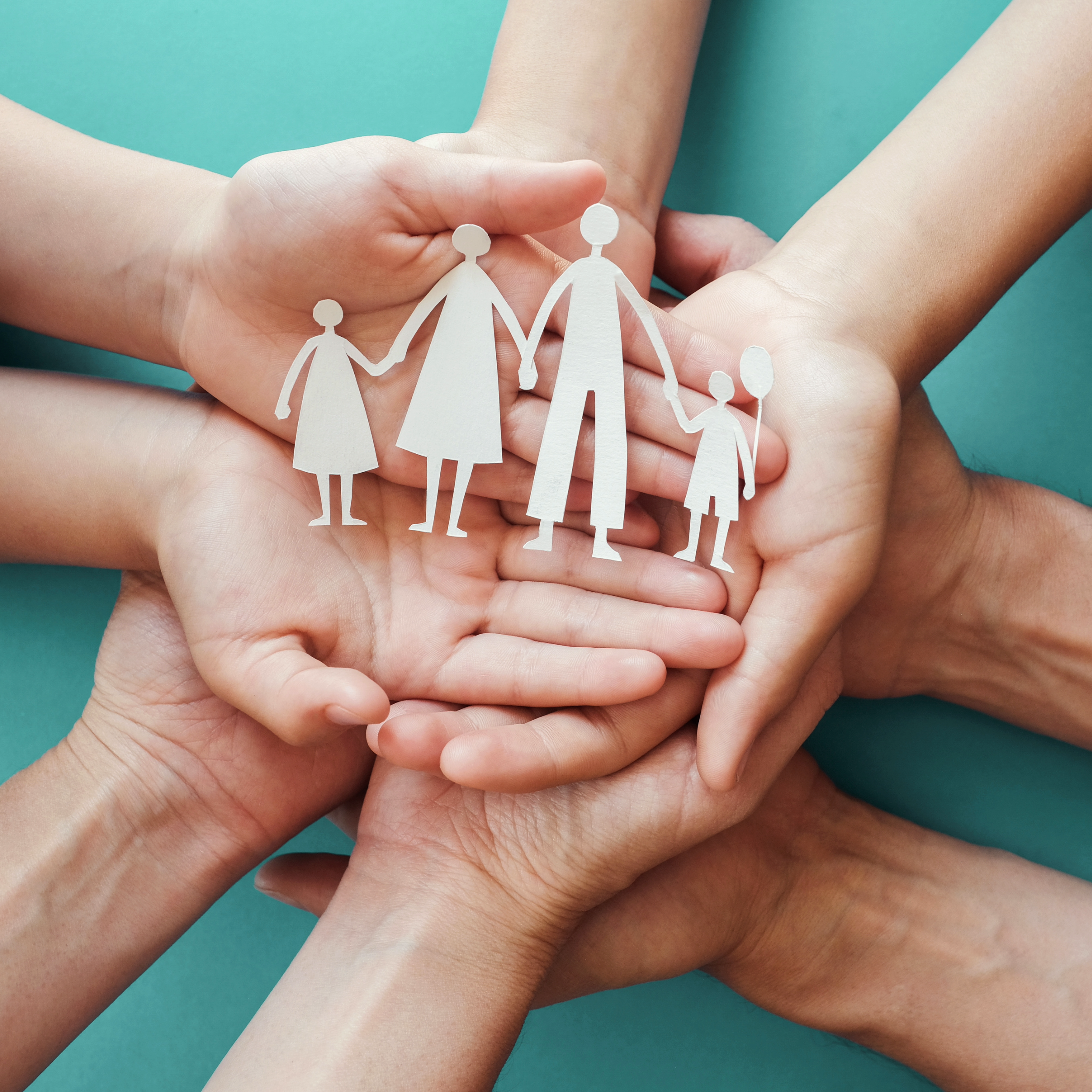 Hands holding paper doll cutouts of a family