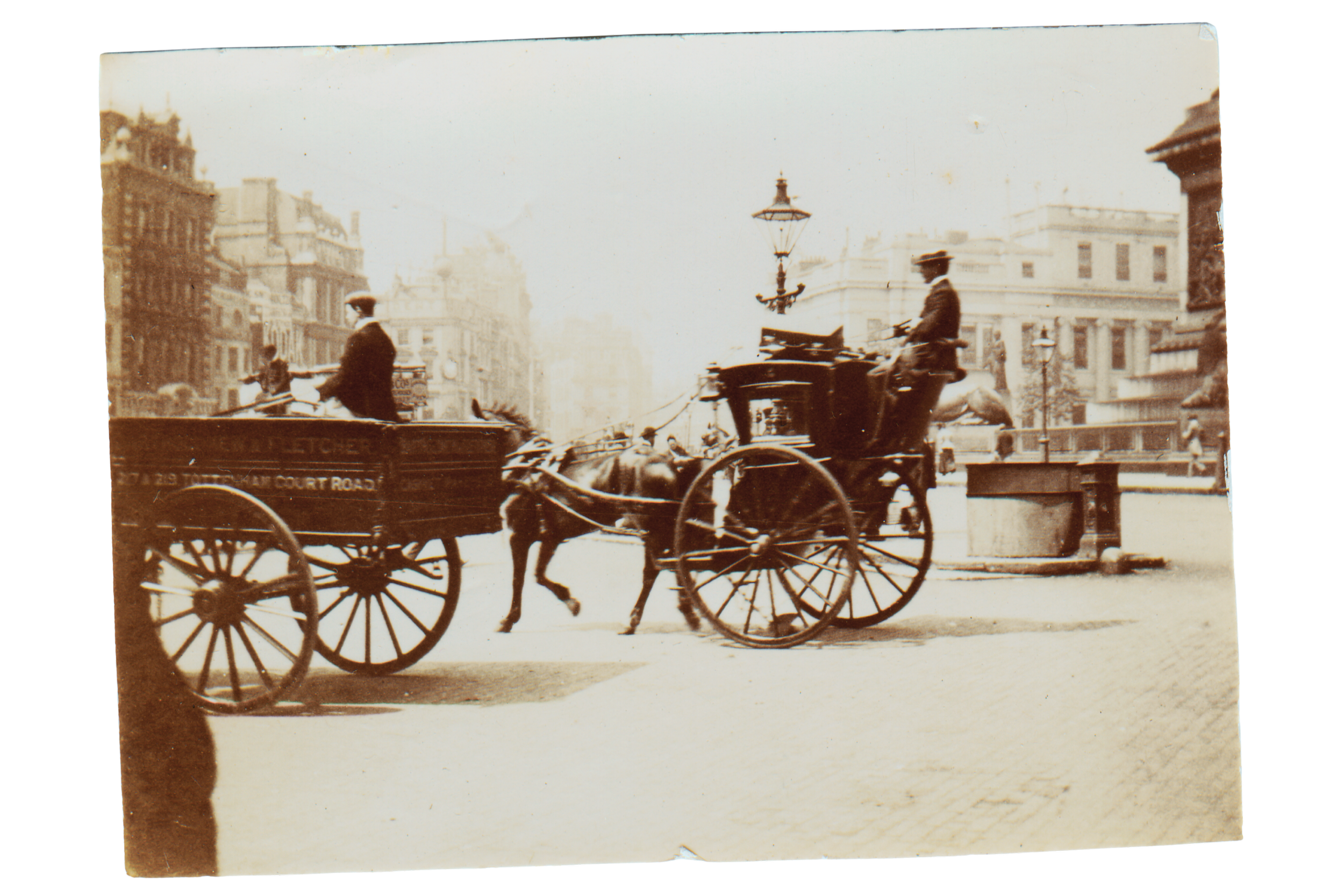 An old sepia-toned photo of a horse-drawn carriage on a city street with buildings, street lamps, and pedestrians in the background.