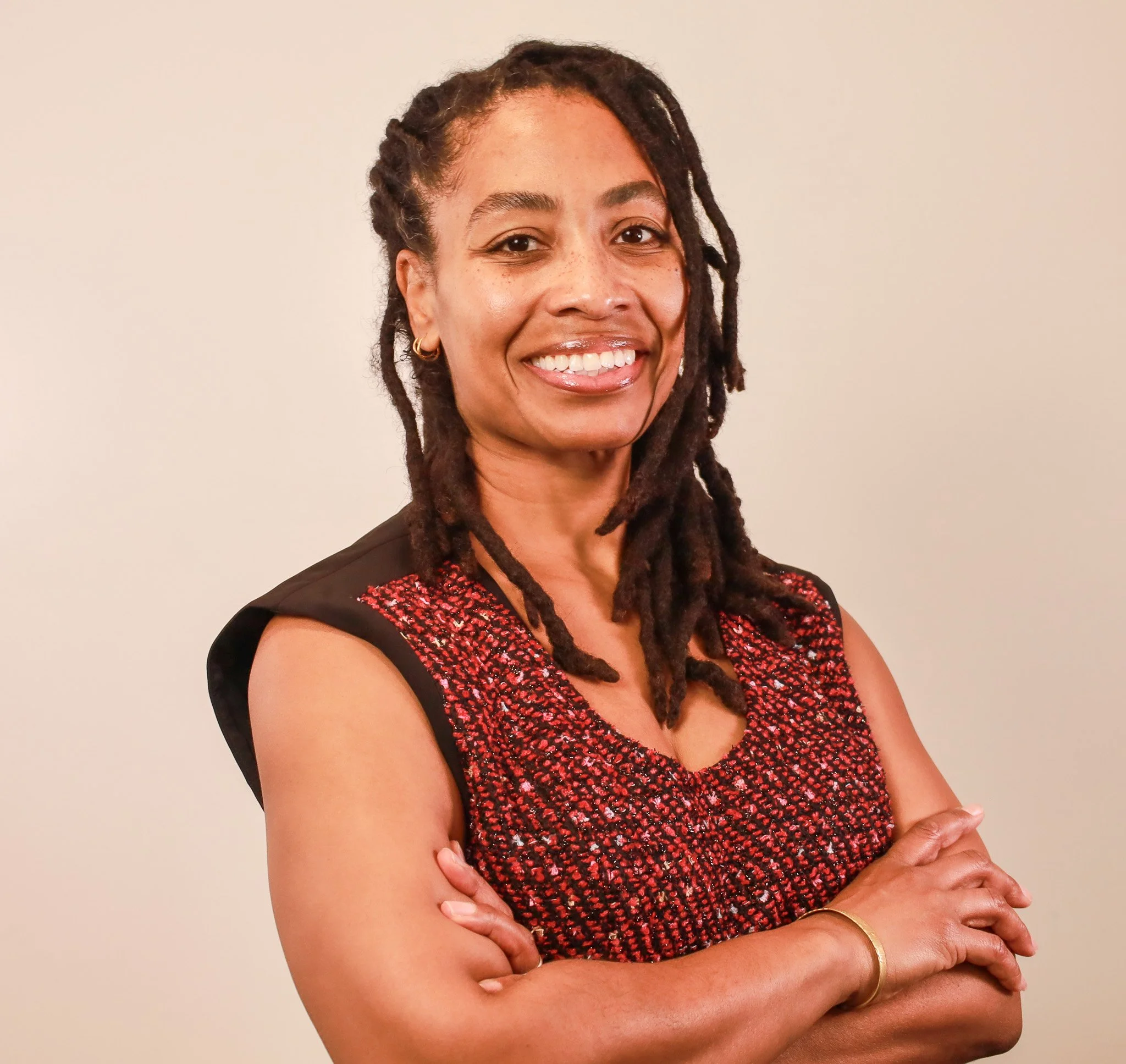 Dr. Sha'llah Brewton, African American physician with dreadlocks, stands smiling confidently  in a business dress.