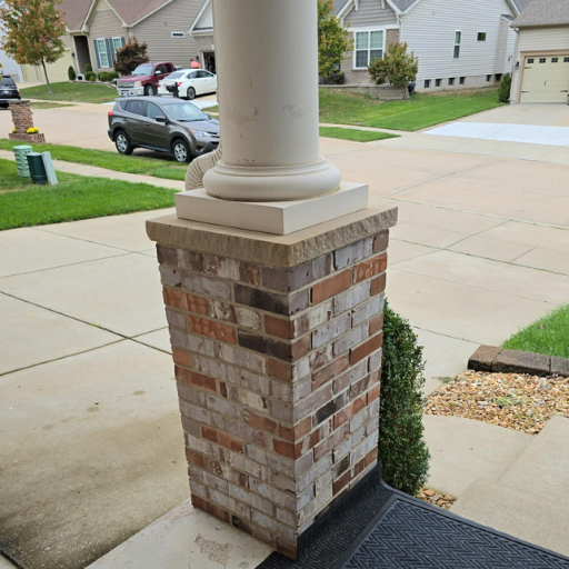 Close-up of brick porch pillar with a white column on top in a suburban neighborhood.