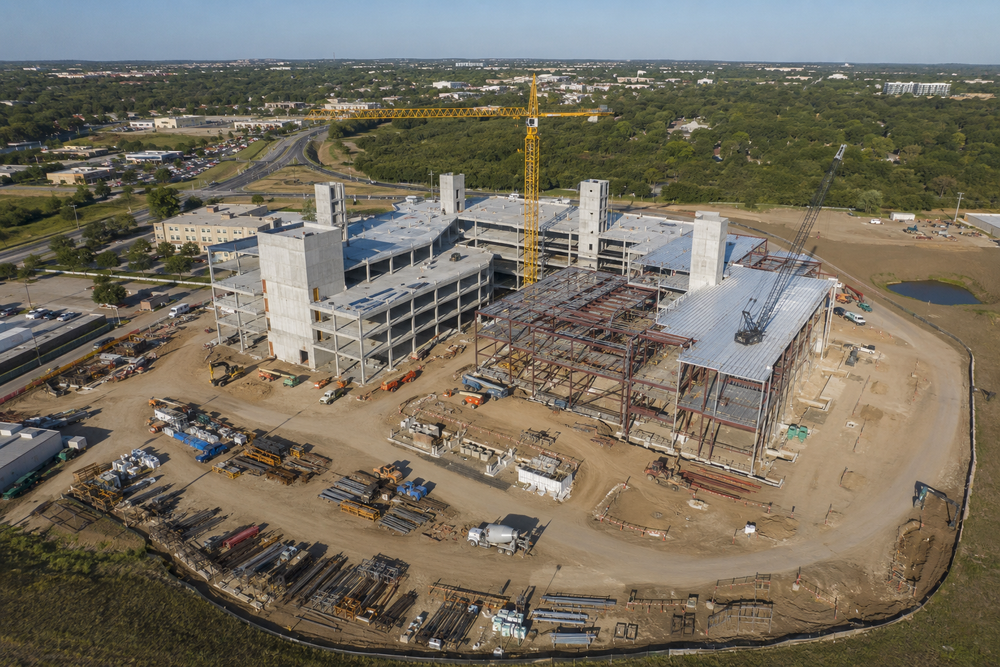 Aerial view of a building under construction, with a tower crane and exposed structure.