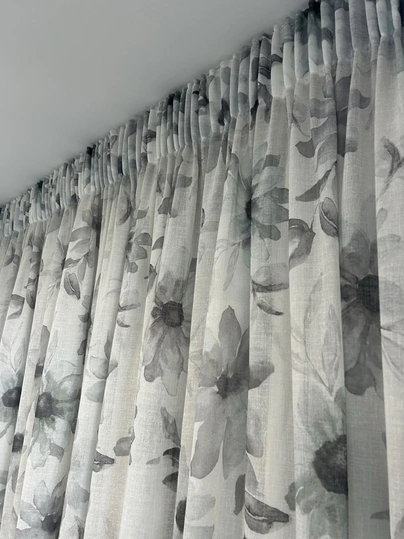 Light-colored floral curtains hanging from a curtain rod.